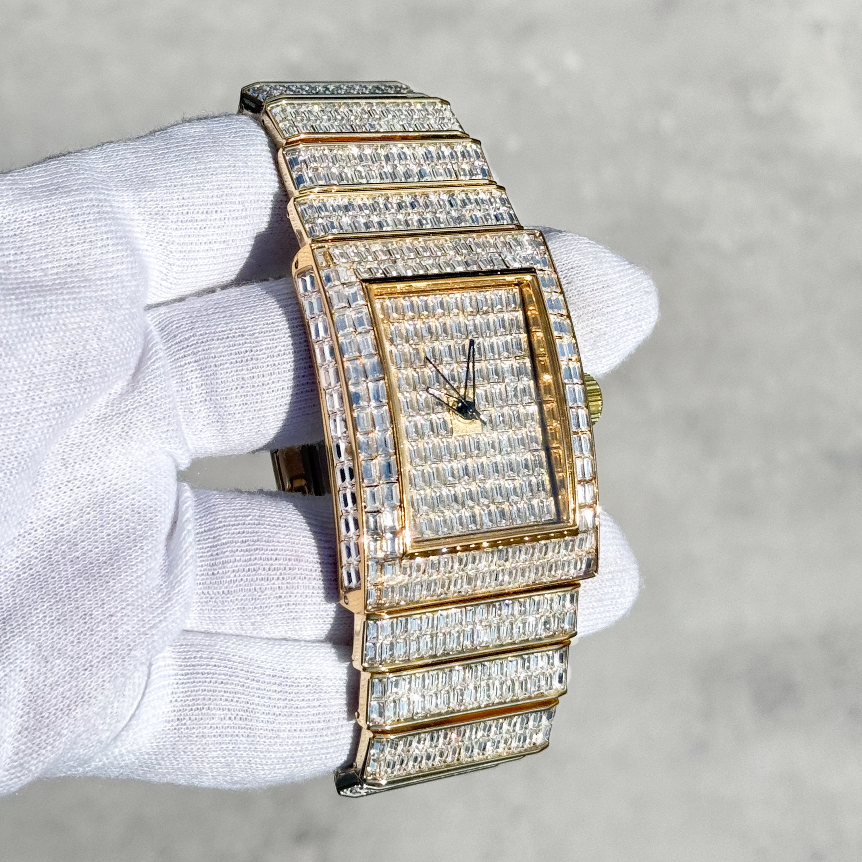 Side view of gold 40mm men's iced rectangular watch featuring baguette diamonds on dial and band.