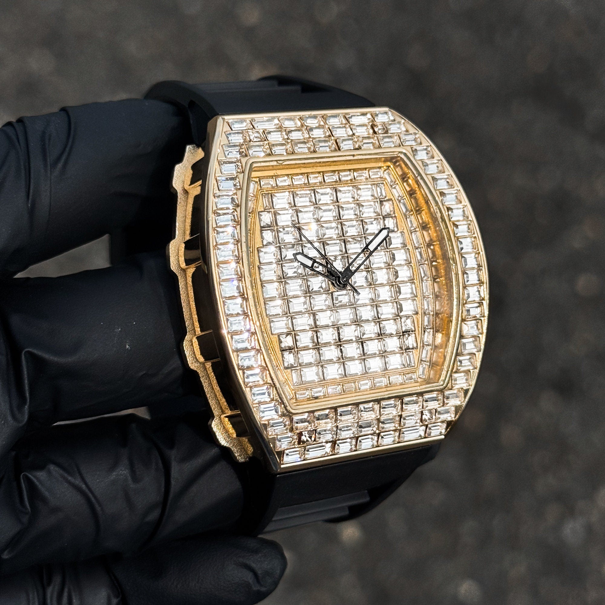 Men’s gold 43mm tonneau watch featuring baguette crystal face and bezel with black silicone strap.