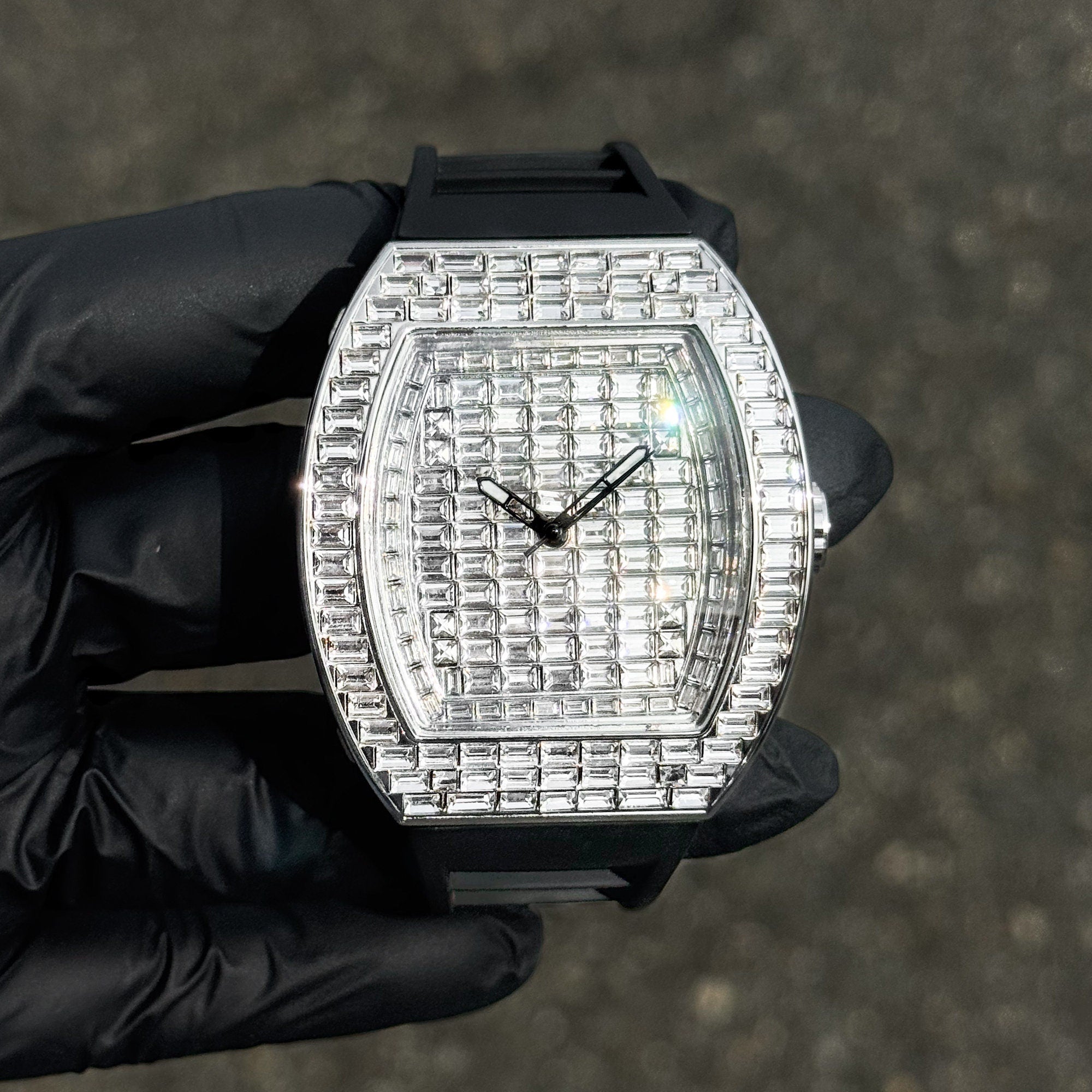 Silver 43mm men’s iced out tonneau watch with baguette crystal dial and durable black silicone band.