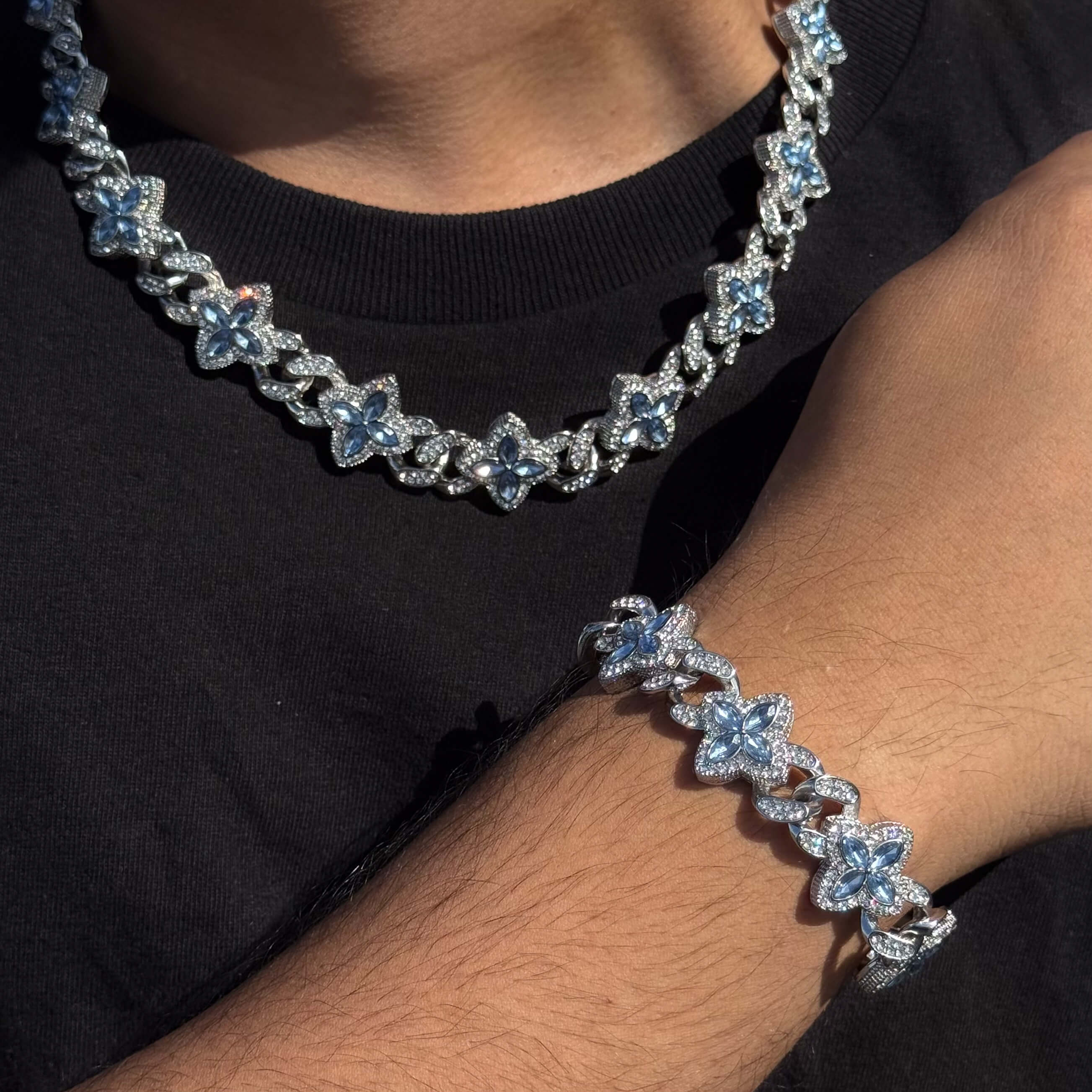 Silver 2-piece iced clover necklace and bracelet set with sparkling blue stones and clover links.