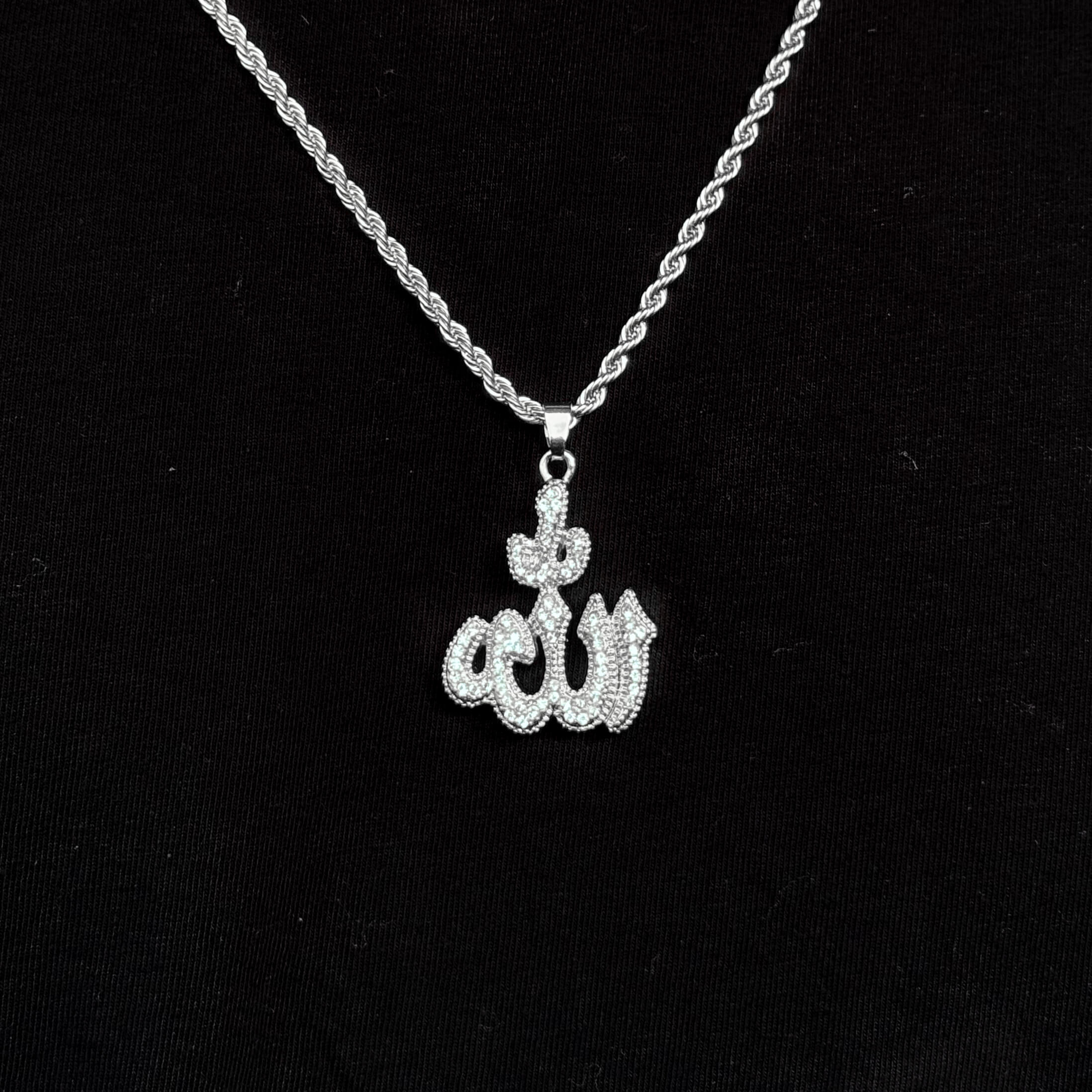 Front view of silver iced-out 26mm Allah pendant hanging from 5mm rope chain on black background.