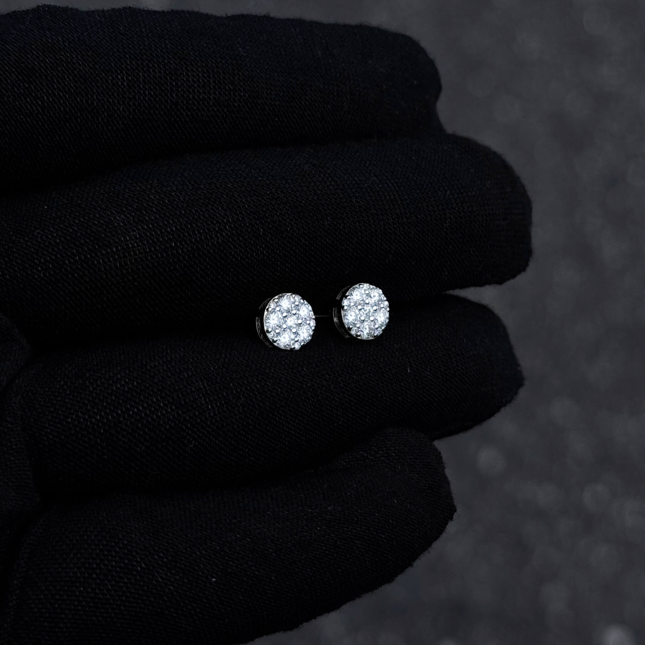 Side angle of 7mm round moissanite cluster diamond stud earrings in sterling silver displayed on glove.