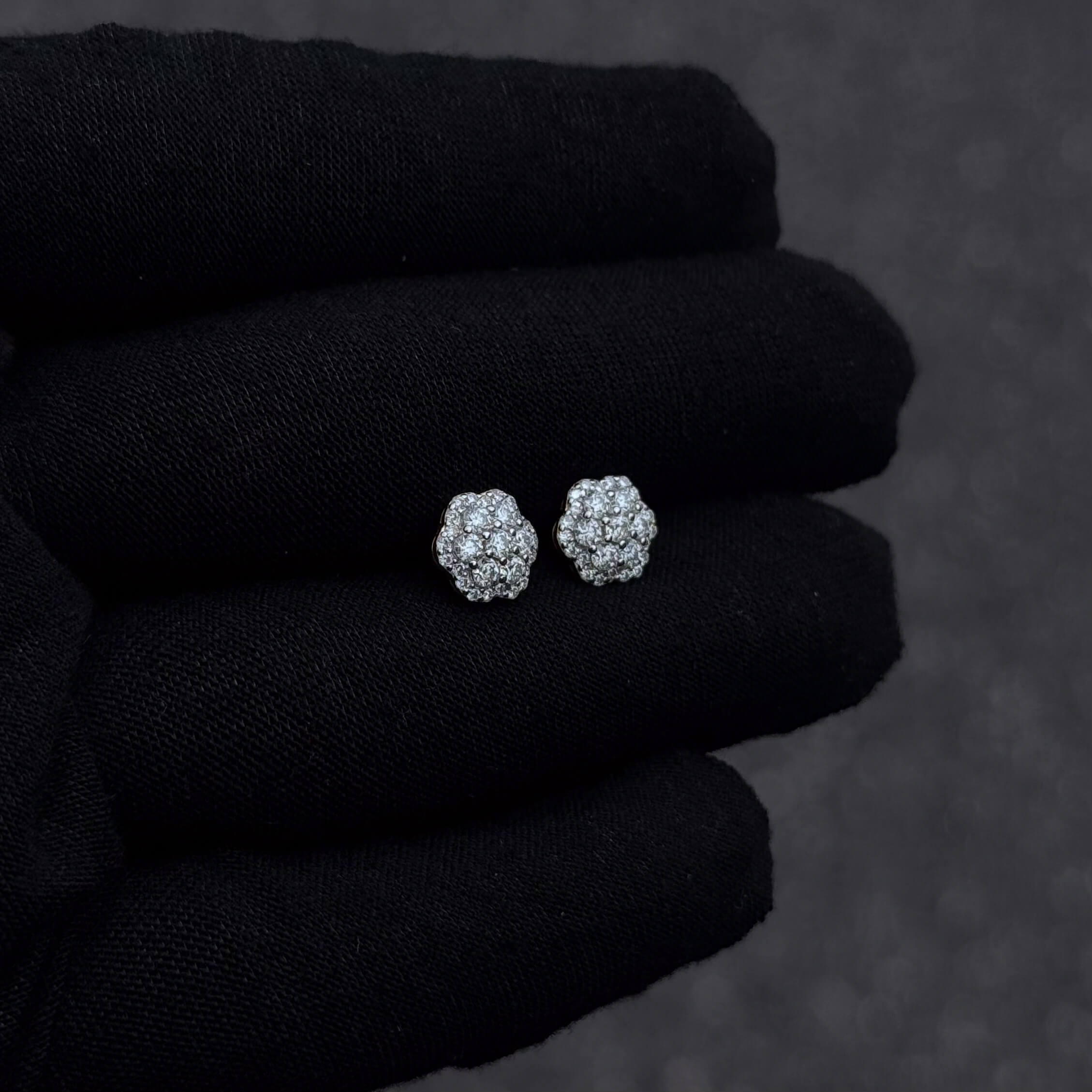 Sterling silver 9mm moissanite flower cluster diamond studs shown against black gloves.
