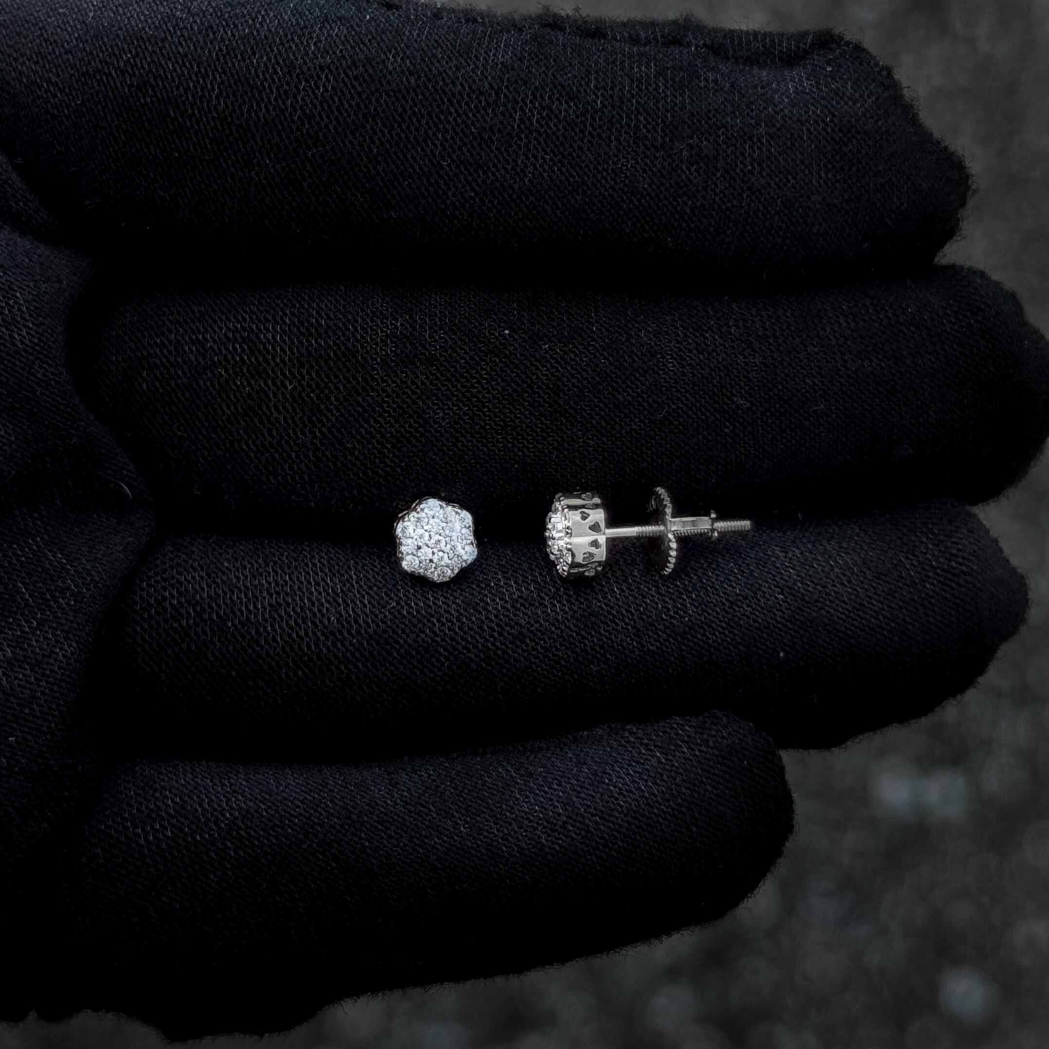 Sterling silver floral moissanite stud earrings with screw-back design shown on glove.
