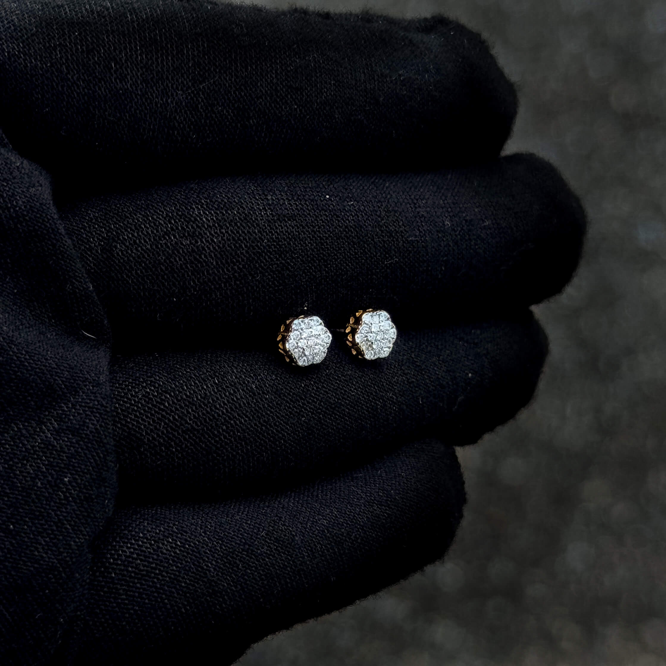 Small 6mm floral moissanite stud earrings in sterling silver displayed on a black glove.