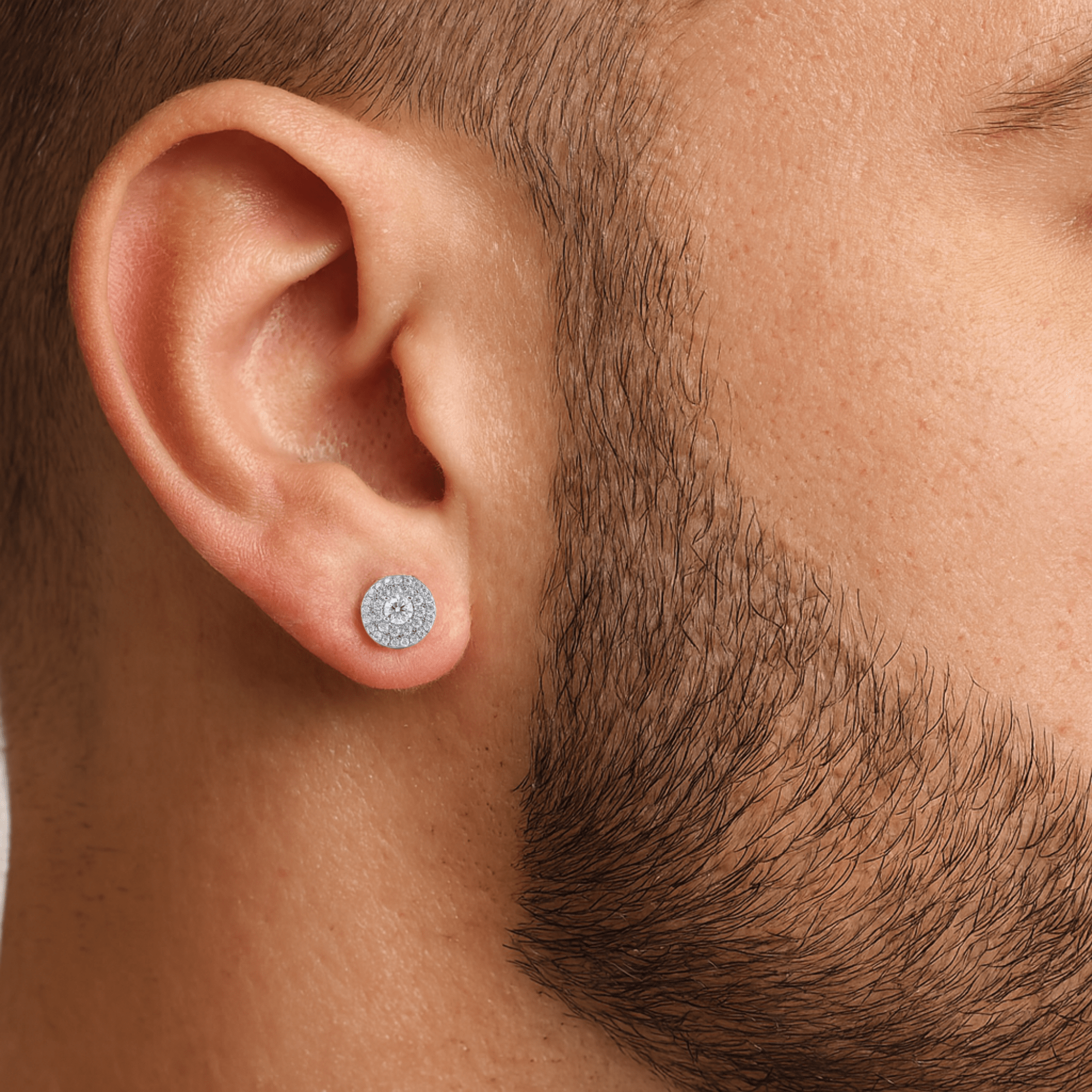 Male model wearing 9mm round moissanite cluster stud earring in sterling silver with halo diamonds.