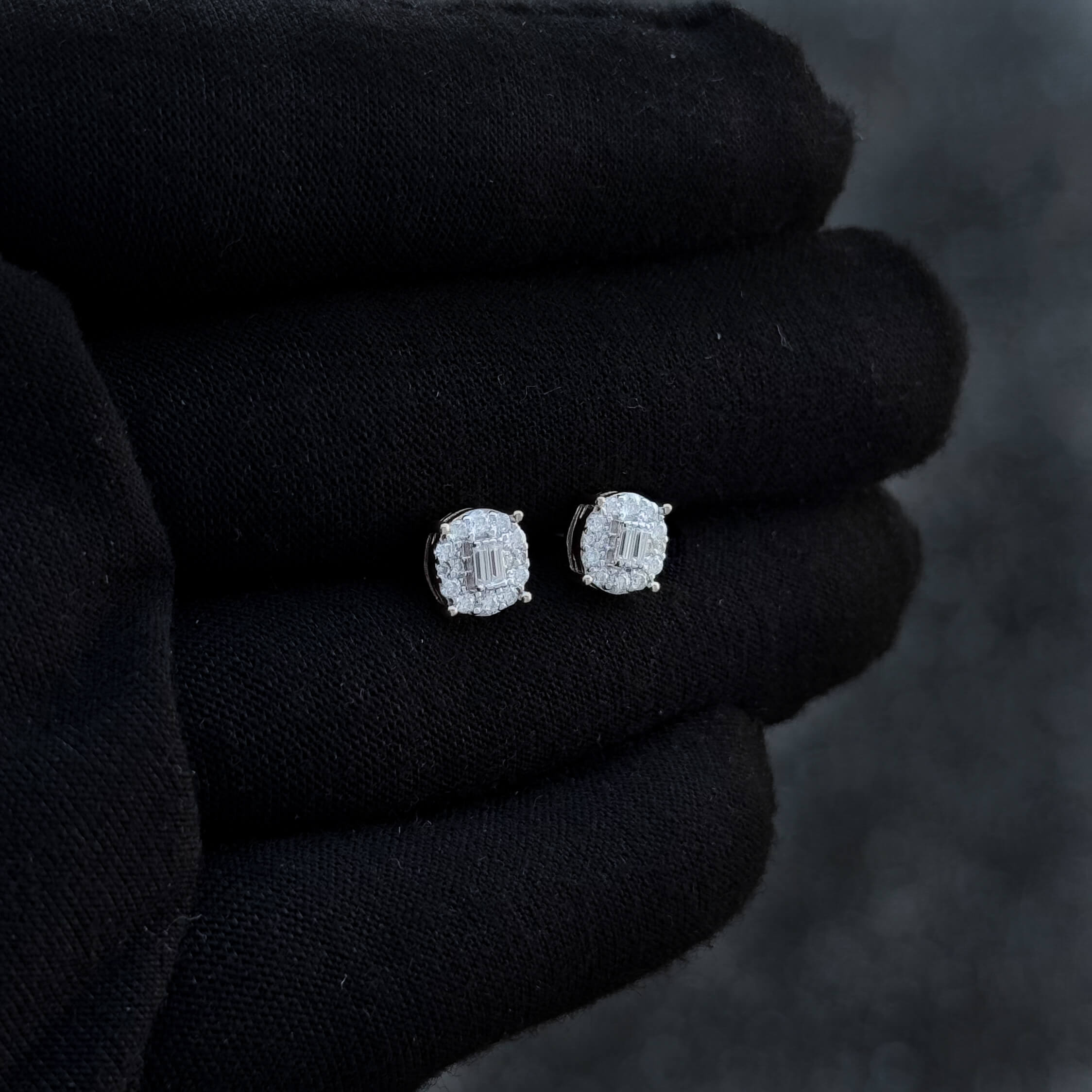 Side-angle view of round 7mm moissanite cluster earrings with silver accents on black glove.