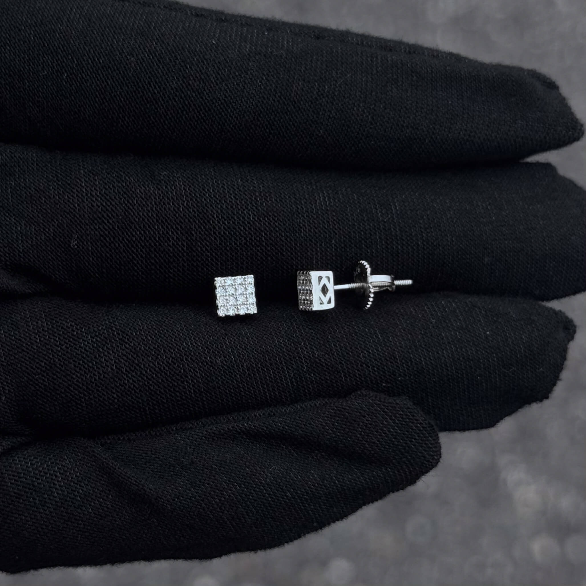 Side and front view of 5mm sterling silver Moissanite square cluster stud earrings on black glove.