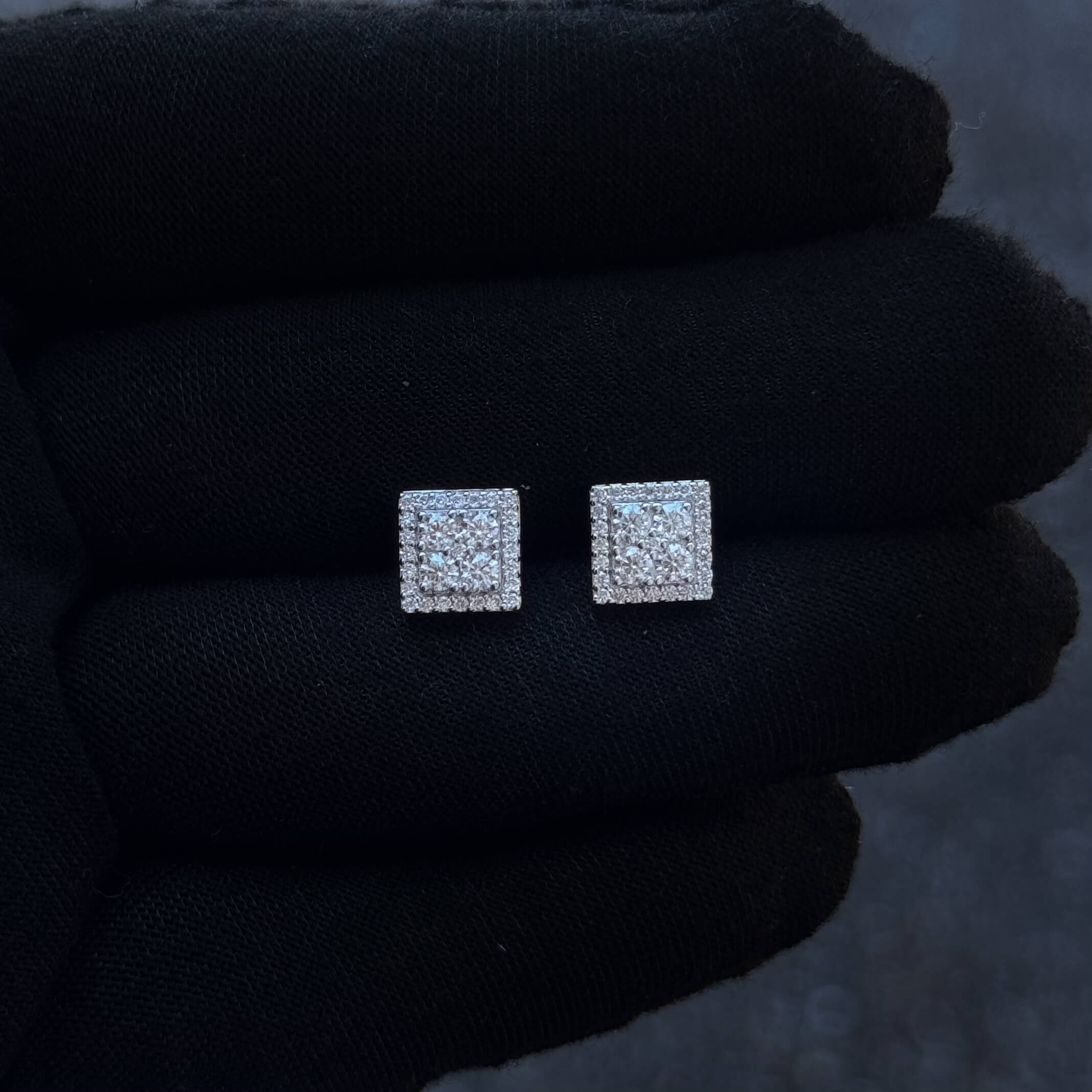 Square sterling silver moissanite cluster diamond studs displayed on black glove.