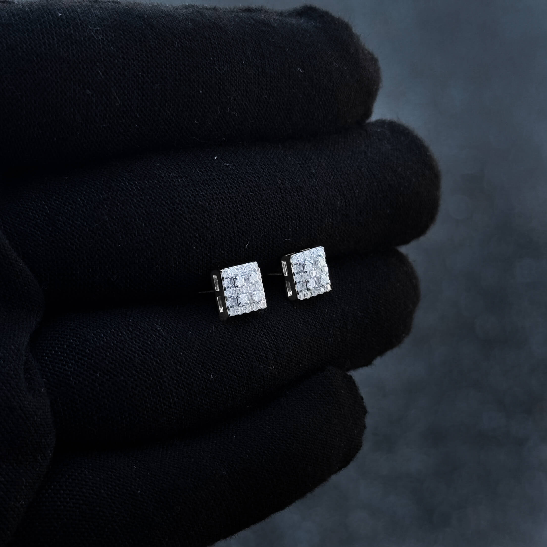 Angled view of 7mm moissanite cluster diamond stud earrings in sterling silver on black glove.