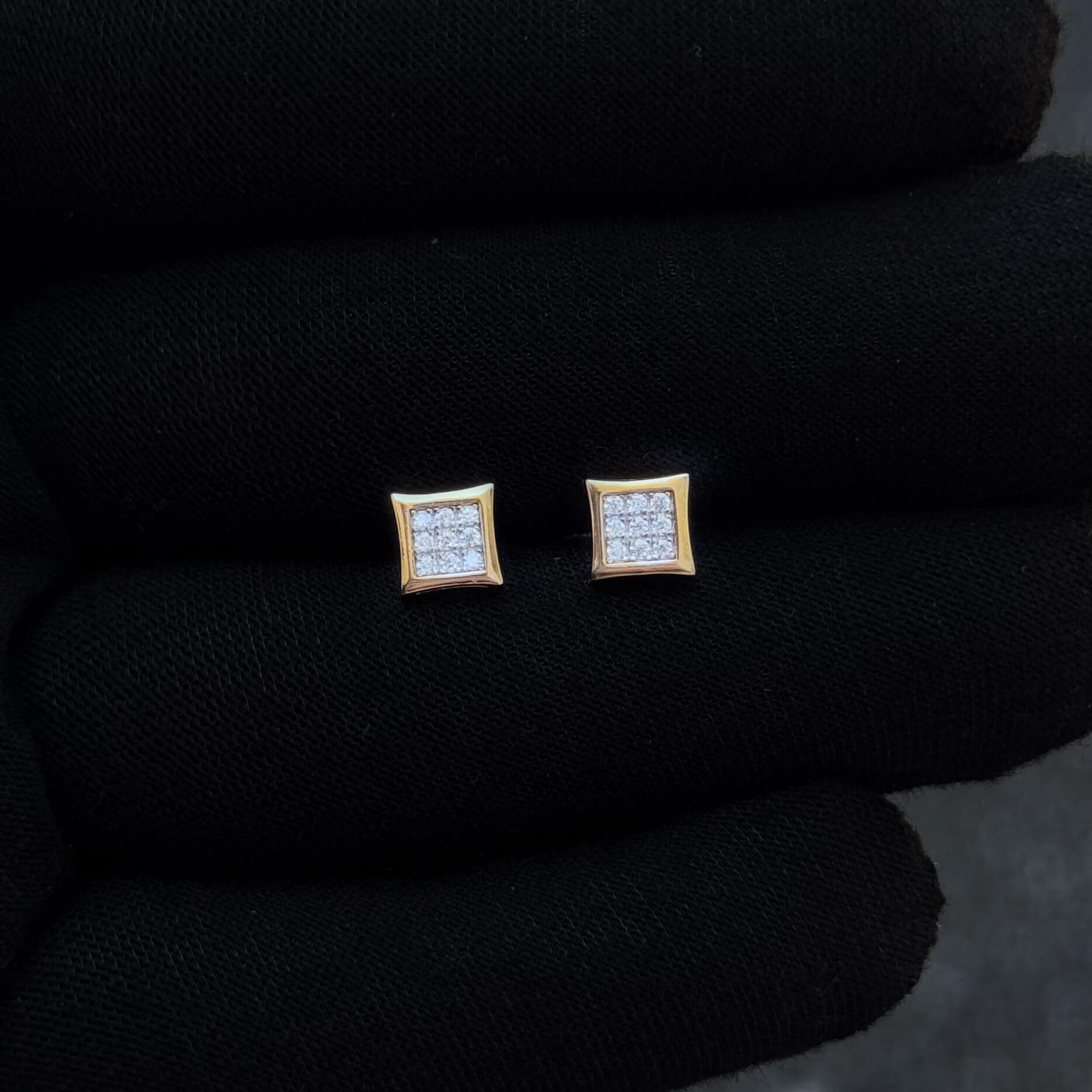 Gold-trim 6mm square moissanite cluster stud earrings displayed on black glove for detail view.