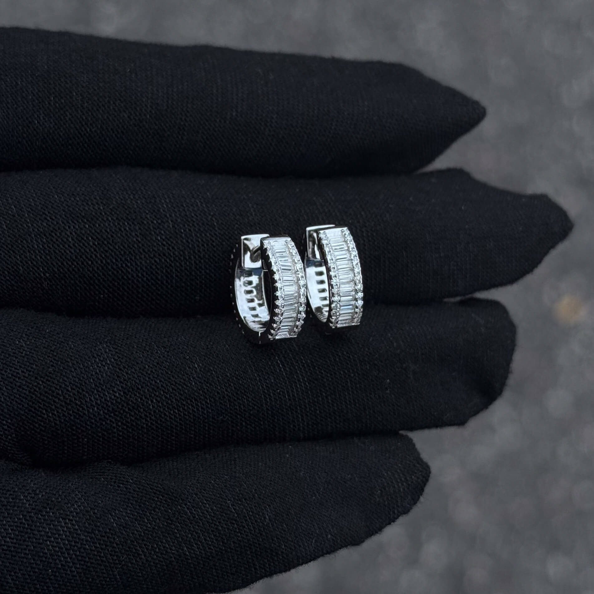 Close-up of silver Baguette Huggie Moissanite Diamond Earrings featuring pavé and baguette stones.