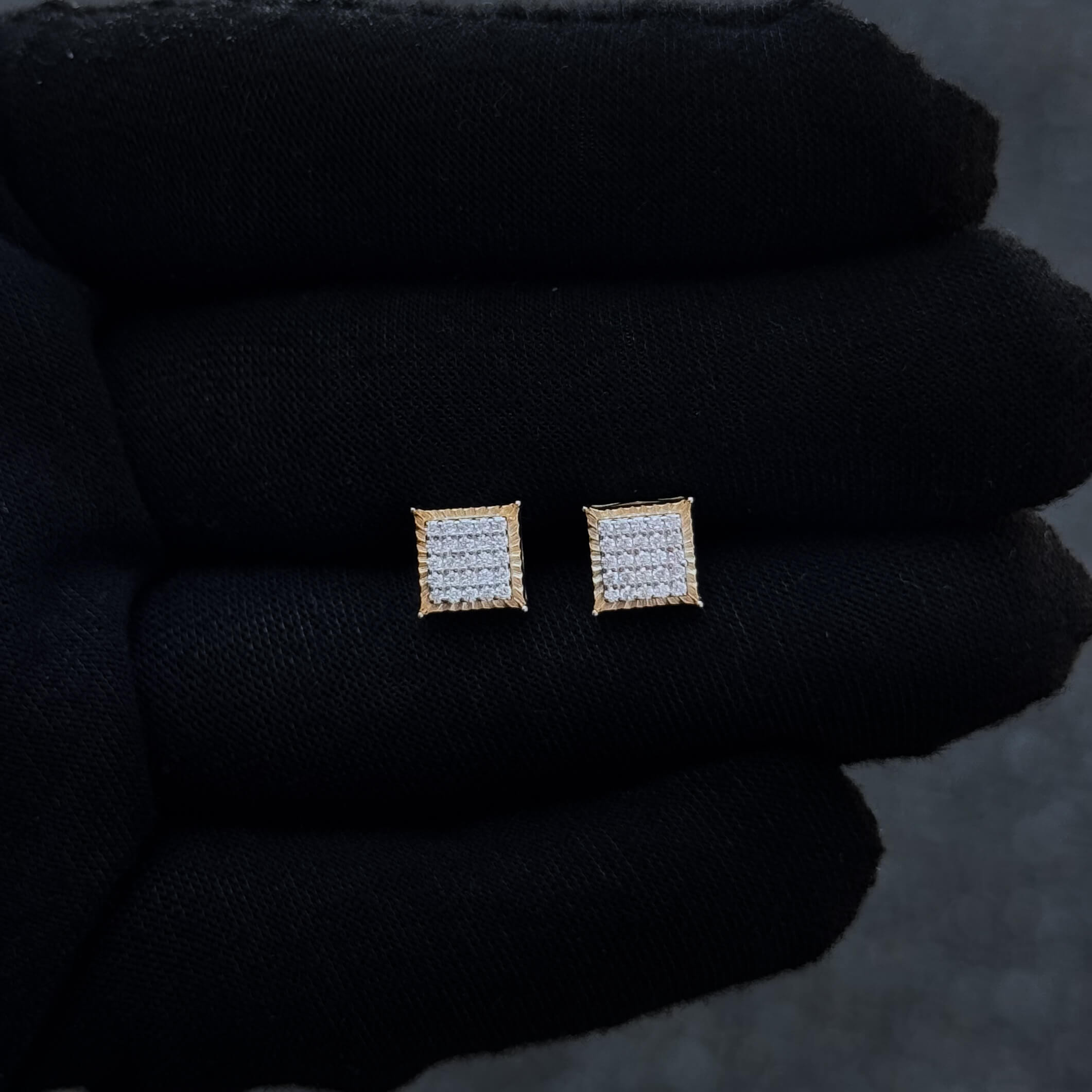 Gold framed 7mm Moissanite cluster stud earrings shown on black glove with pavé diamond detail.