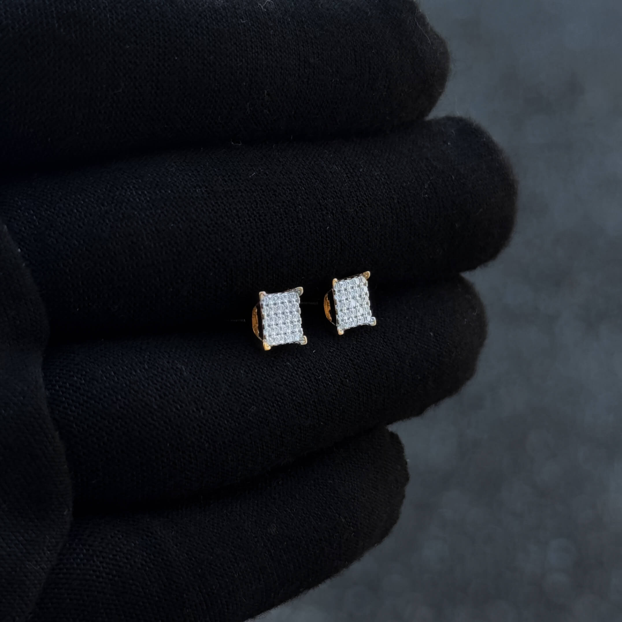 Gold-accent 6mm square Moissanite cluster earrings displayed at an angled view on black glove.