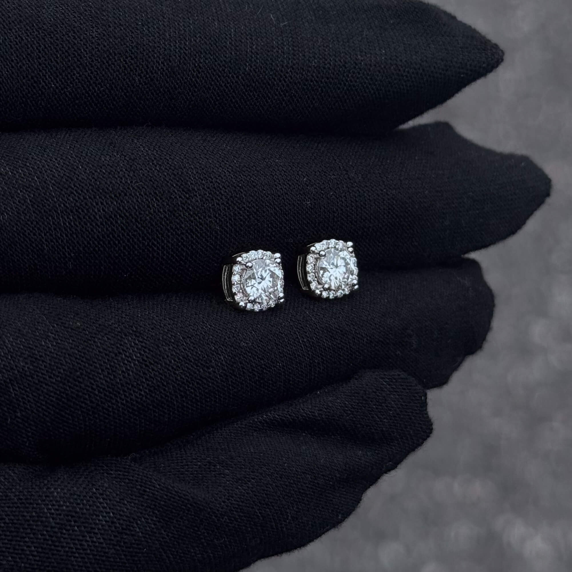 7mm round moissanite cluster stud earrings in sterling silver displayed on black glove for detail.