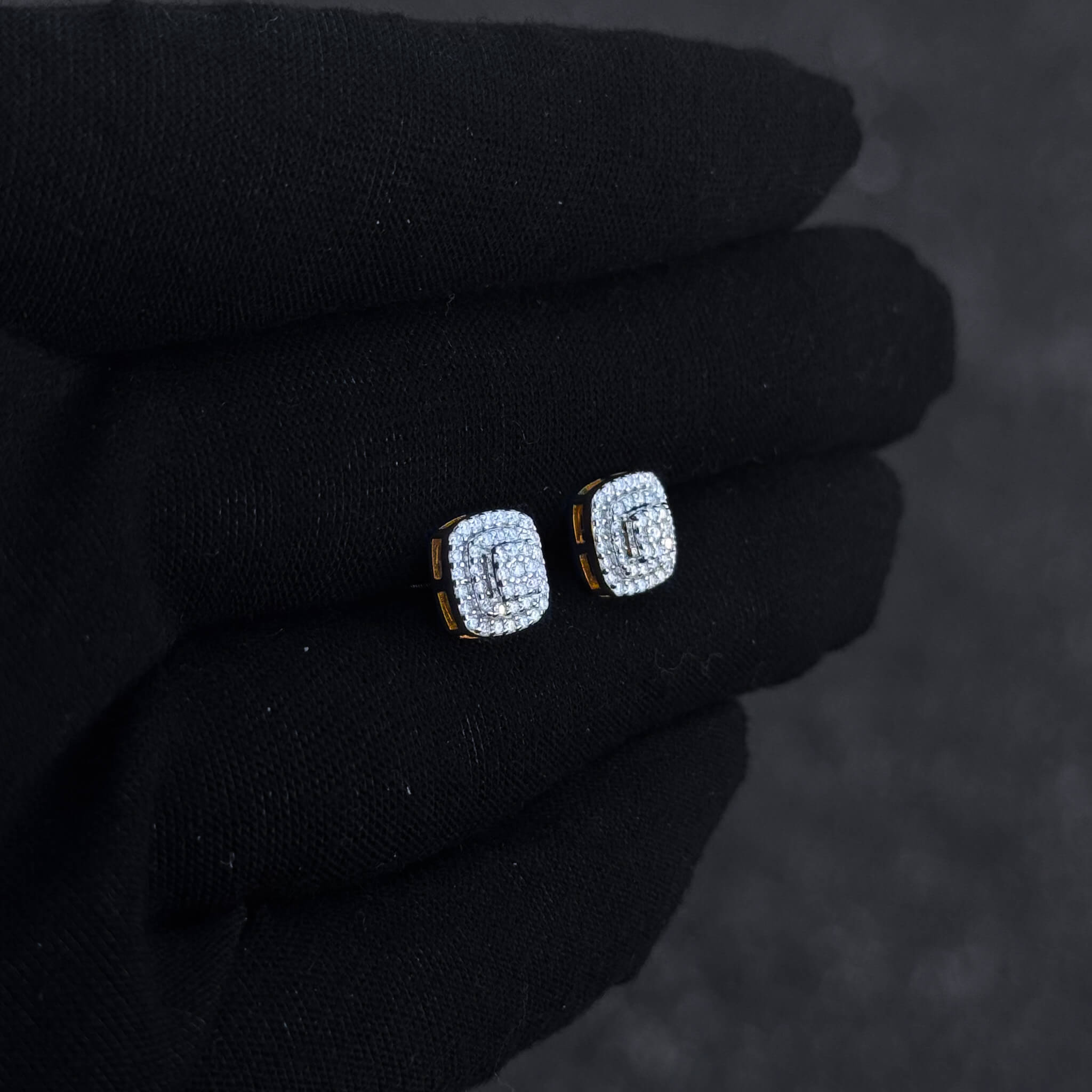 Gold-trim square moissanite cluster earrings shown on black glove, featuring triple halo diamond detail.