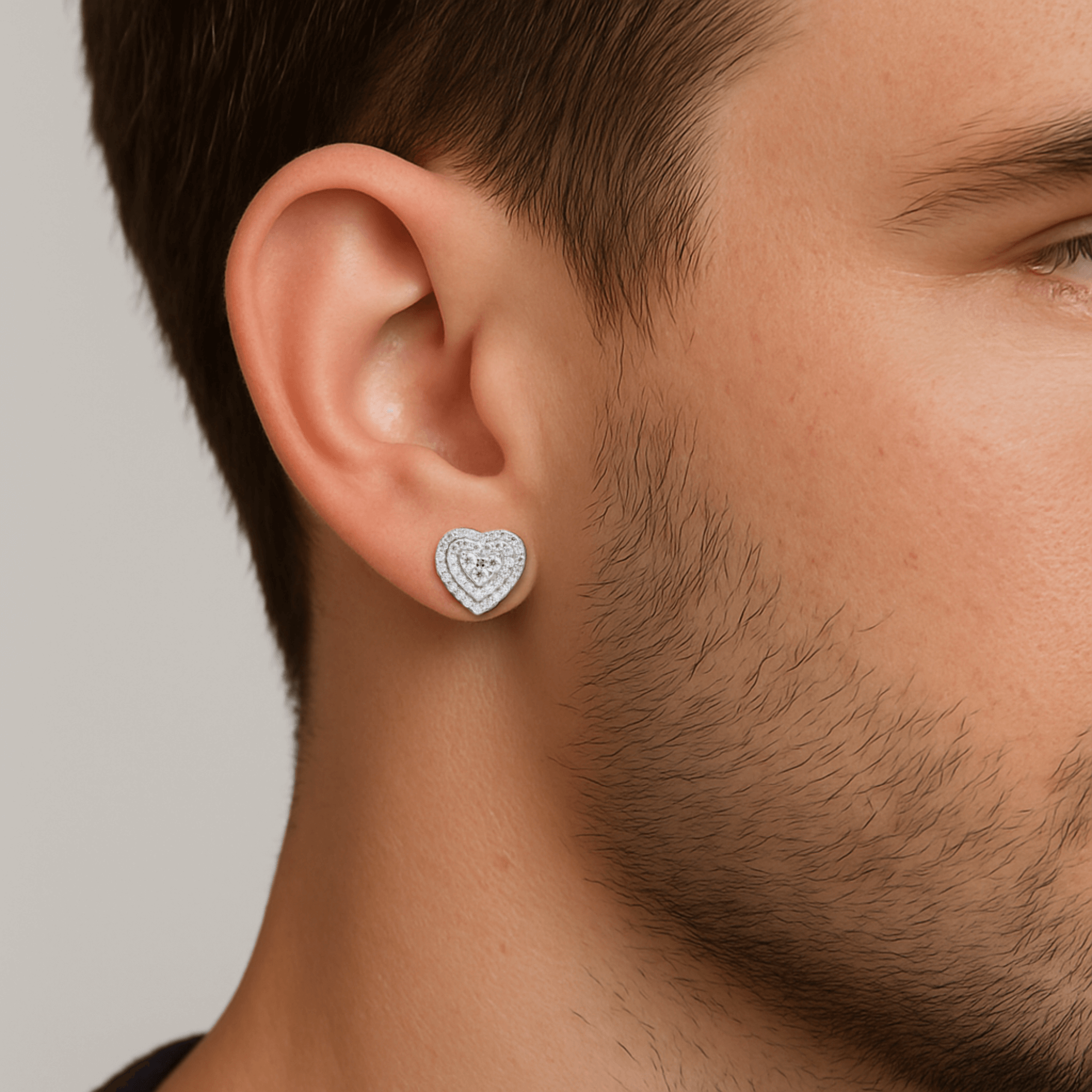 Man wearing 9mm heart moissanite cluster earrings in sterling silver with layered halo design.