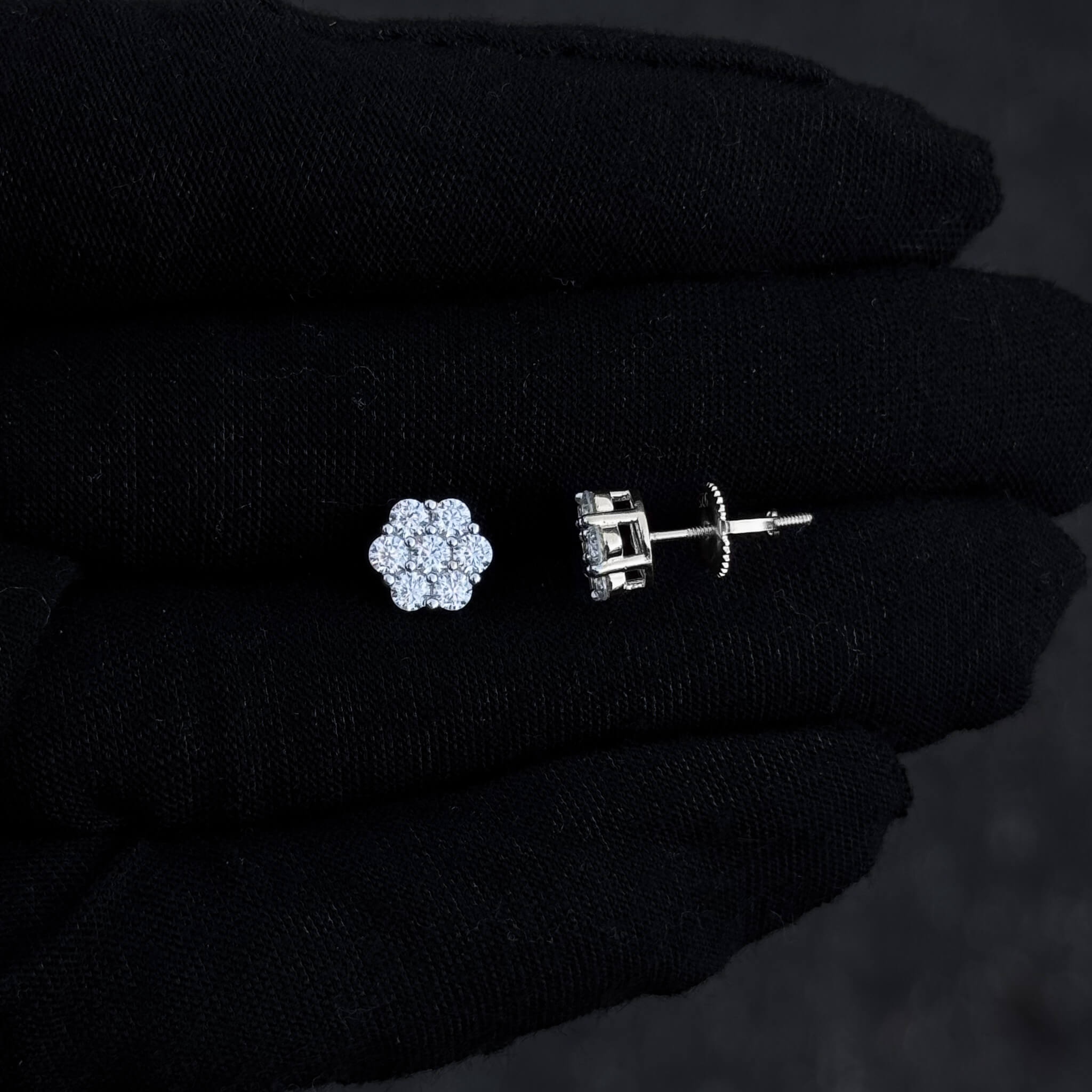 Close-up of one floral moissanite stud and screw-back post in sterling silver setting.
