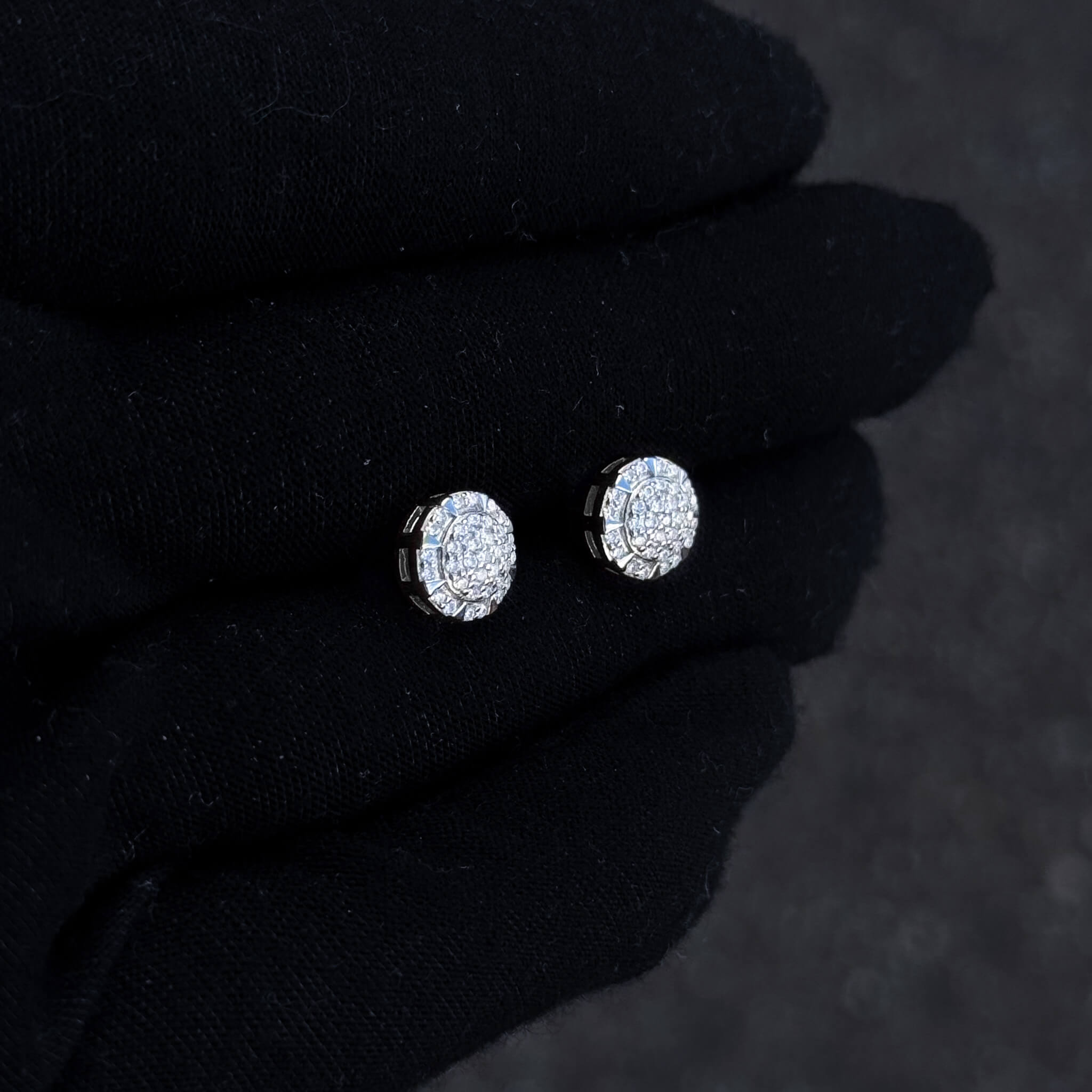 Small round moissanite cluster stud earrings shown on black glove with bright pavé detailing.