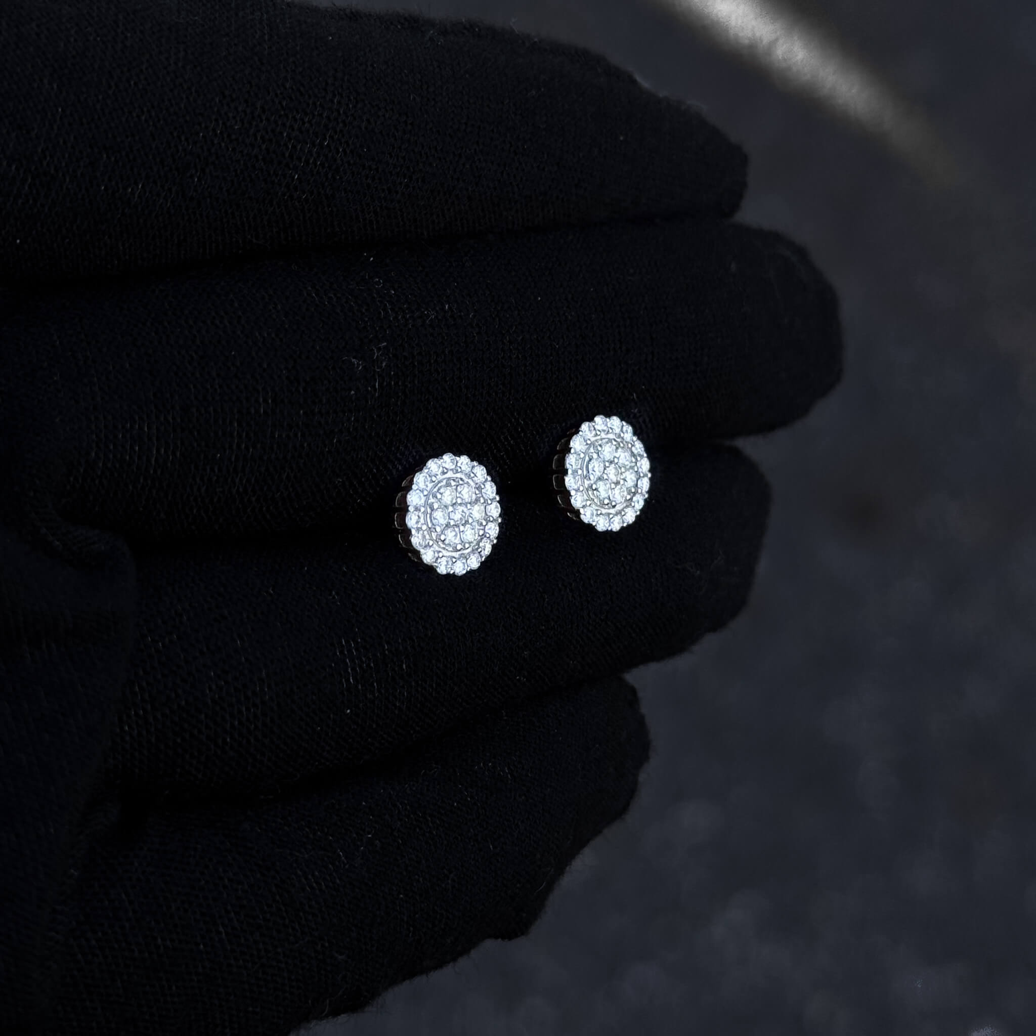Small round 8mm moissanite and diamond cluster stud earrings displayed on black glove.