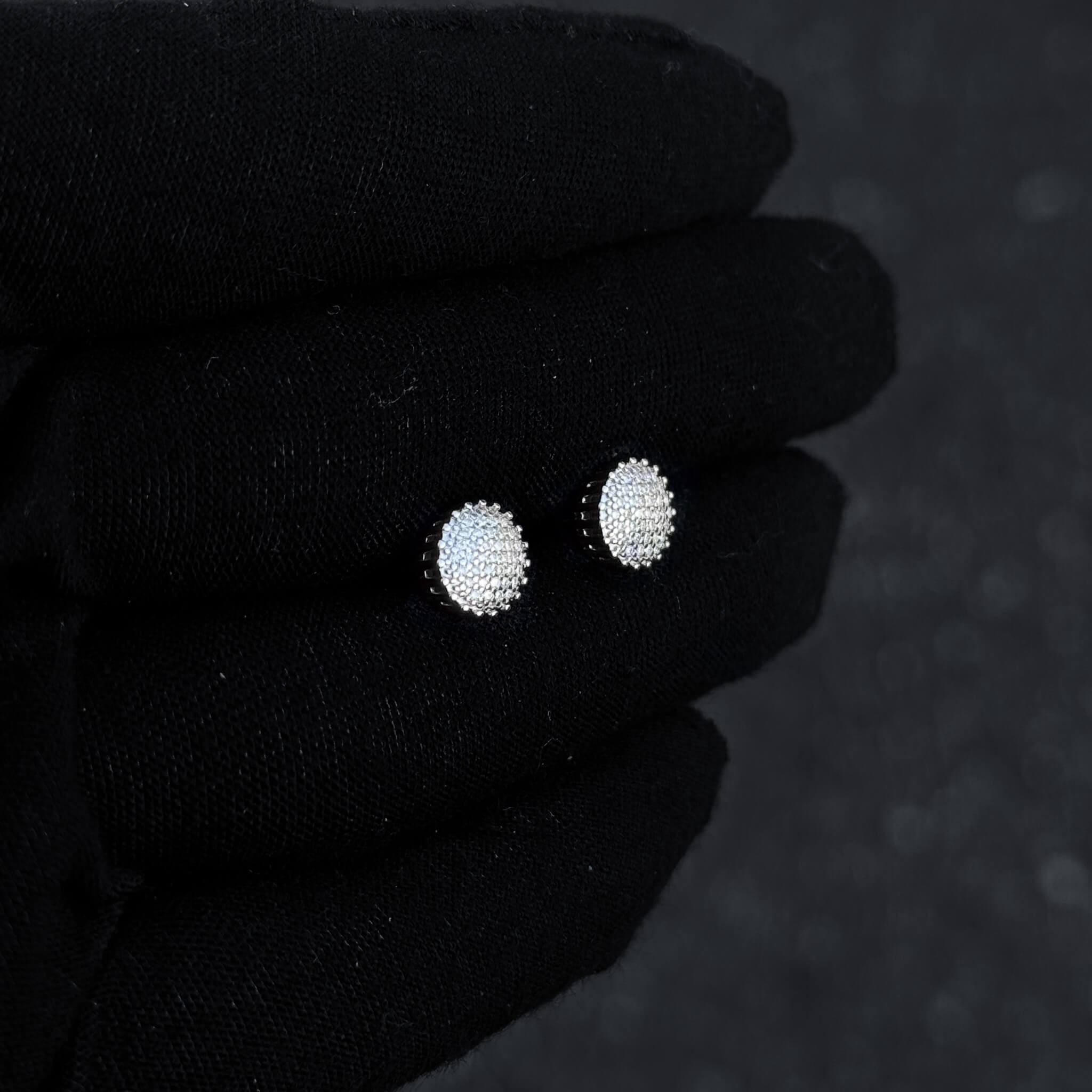 Sterling silver 8mm moissanite cluster earrings with bright diamond sparkle on glove display.