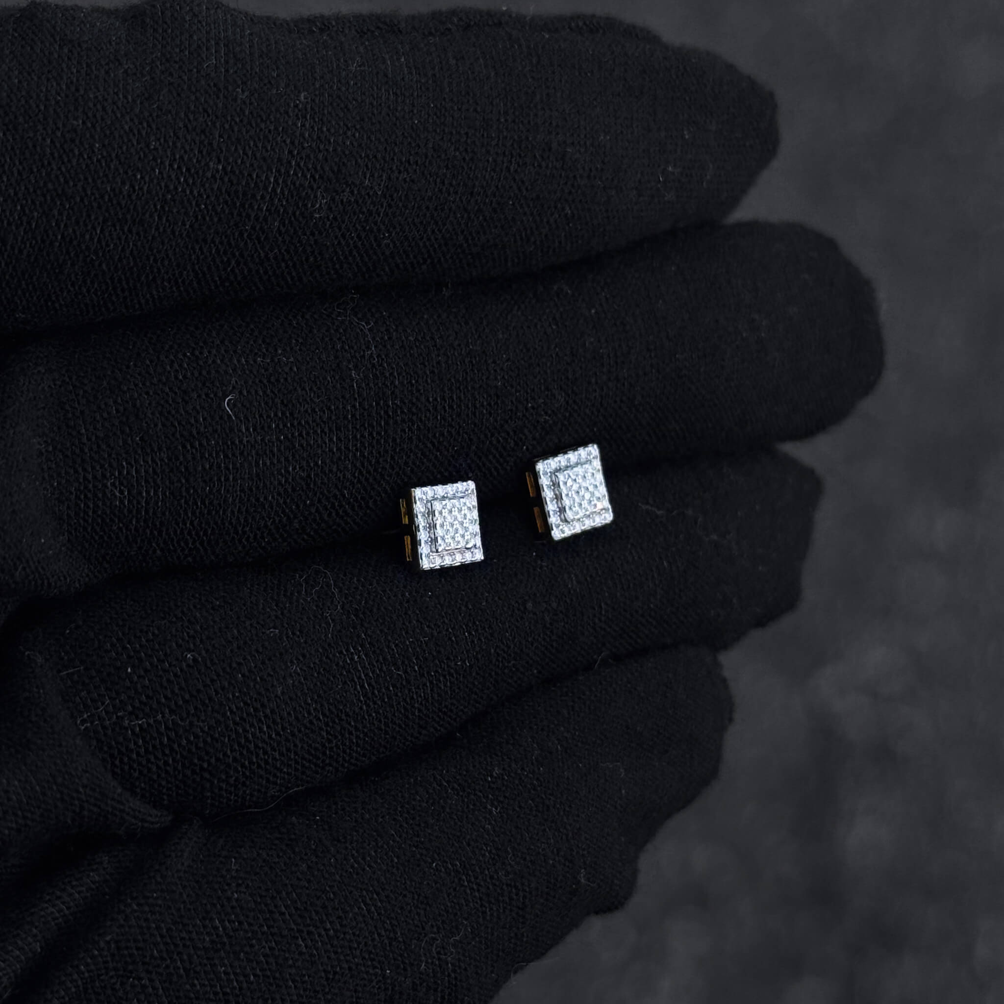 Small 6mm sterling silver square moissanite cluster studs shown on black glove for size comparison.