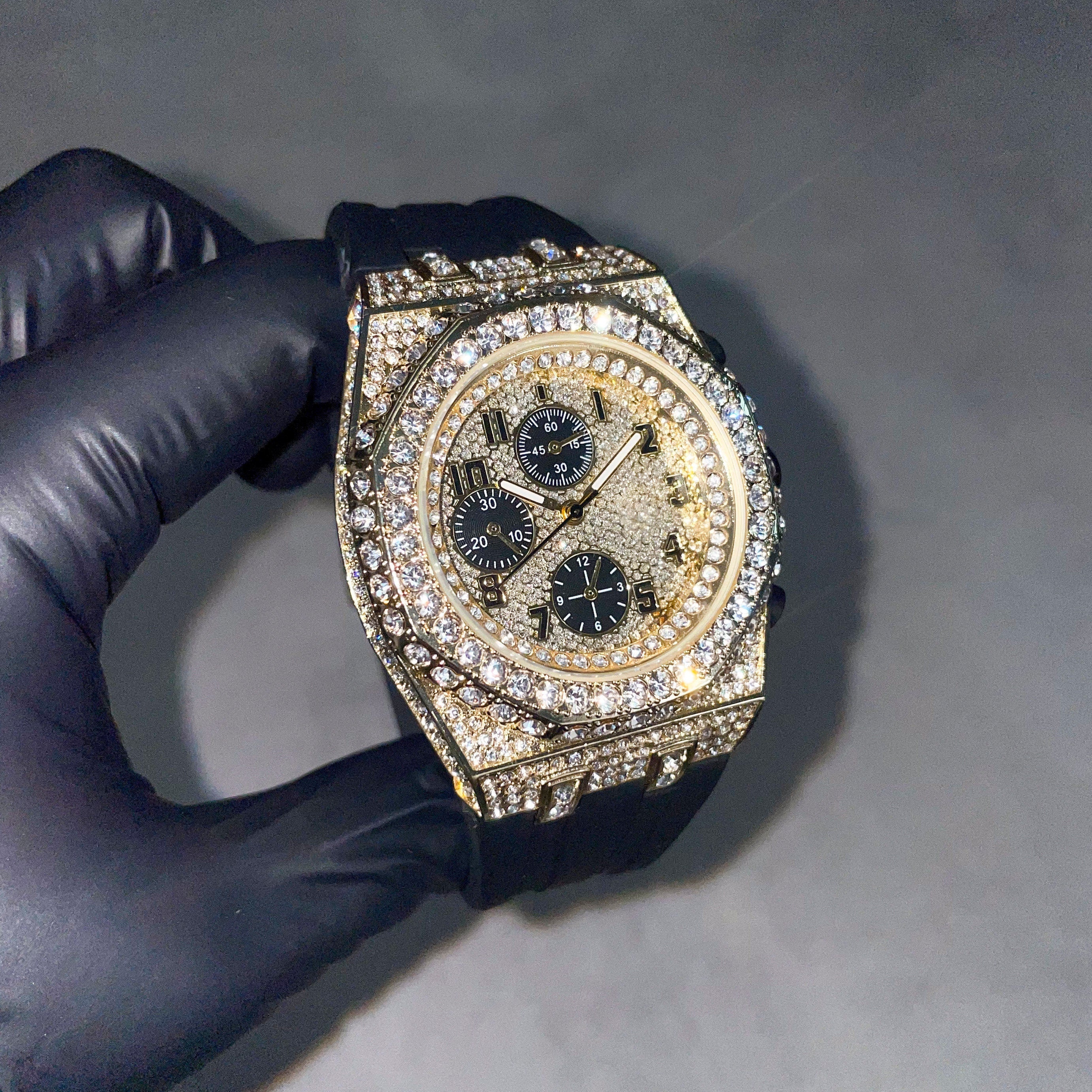 Men's 43mm gold iced out octagon bezel diamond watch with black silicone band and quartz chronograph dial.