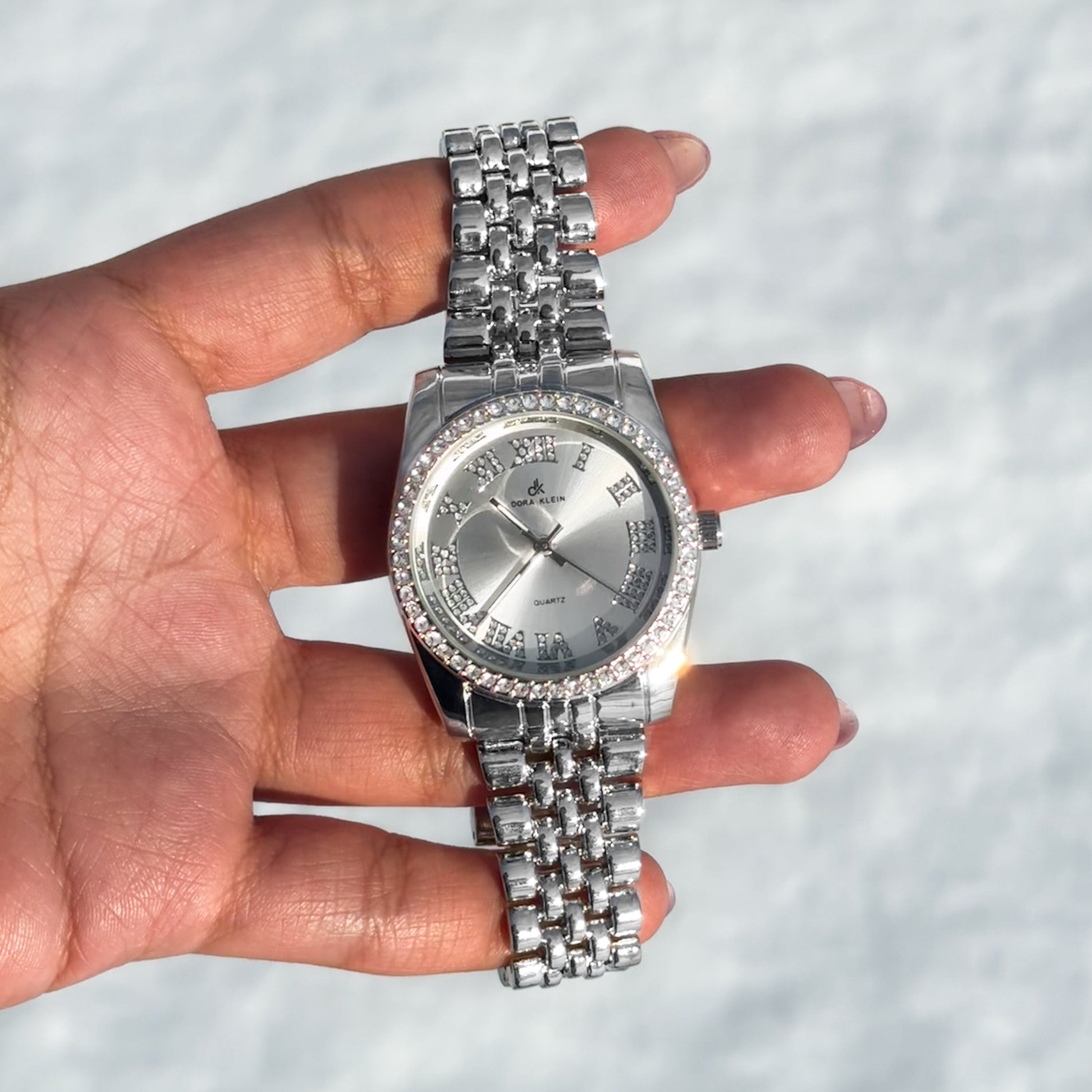 Silver Women's 35mm quartz watch with Roman dial, crystal-studded bezel and polished metal band.