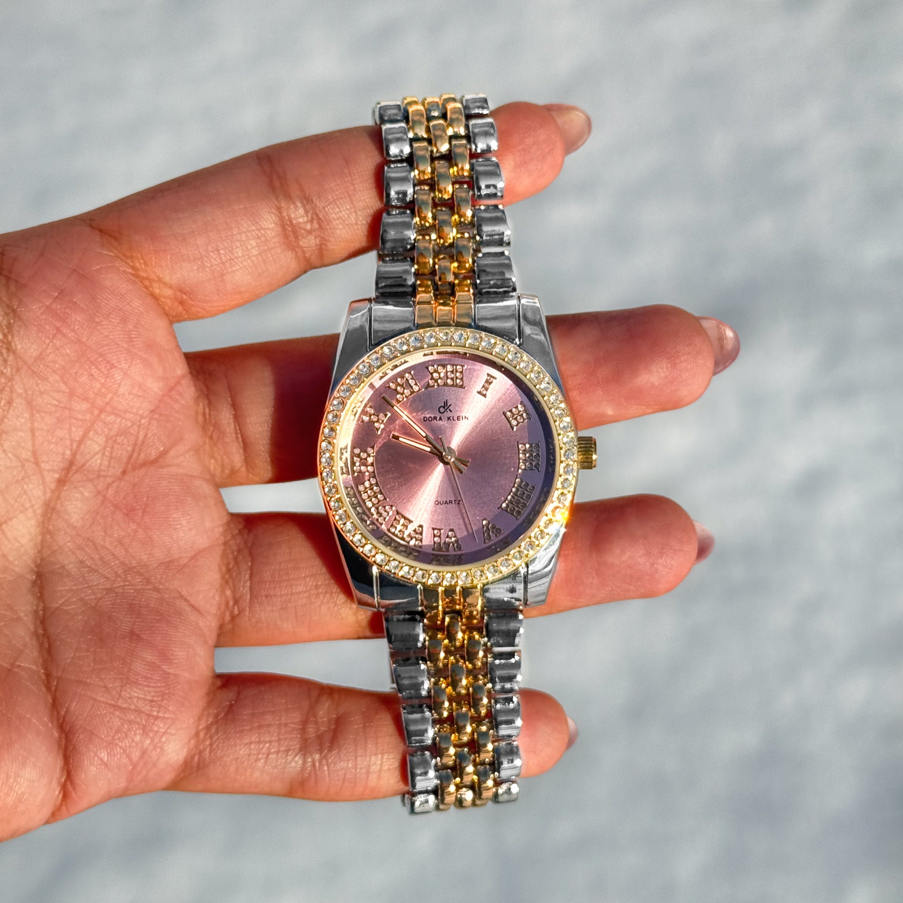 Two-tone Women’s 35mm Roman dial watch with pink face and diamond-studded bezel, metal bracelet.