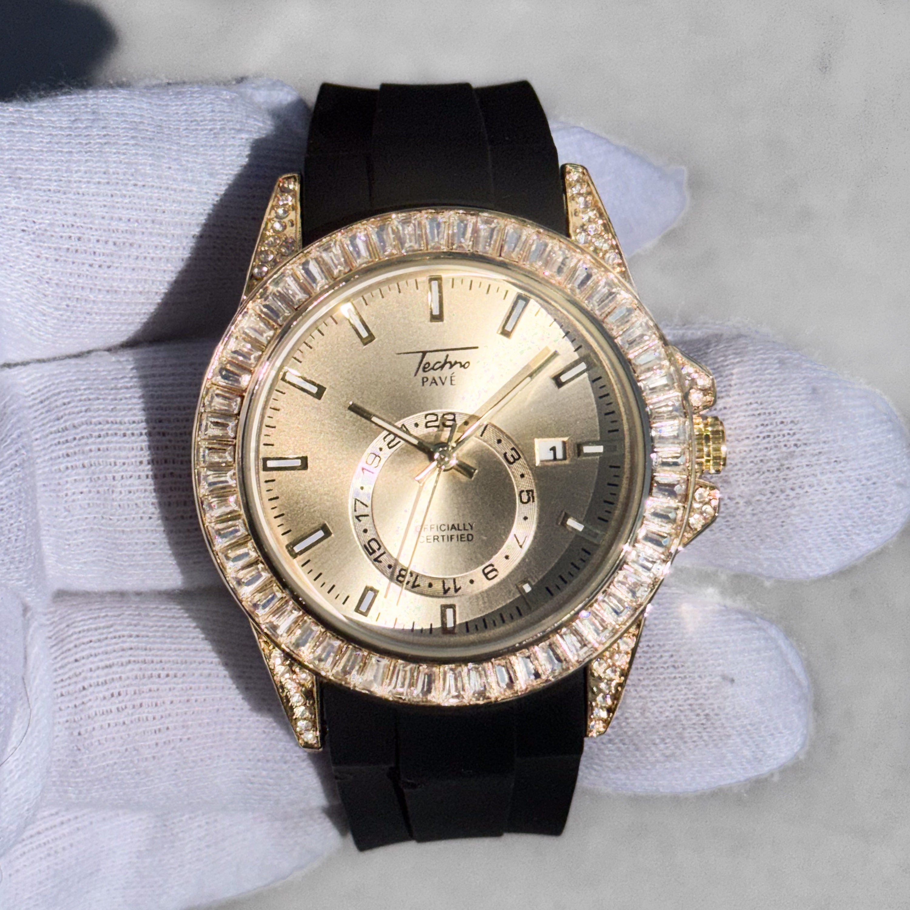 Gold men’s 42mm diamond watch with silicone strap, baguette bezel detailing, and quartz date movement.