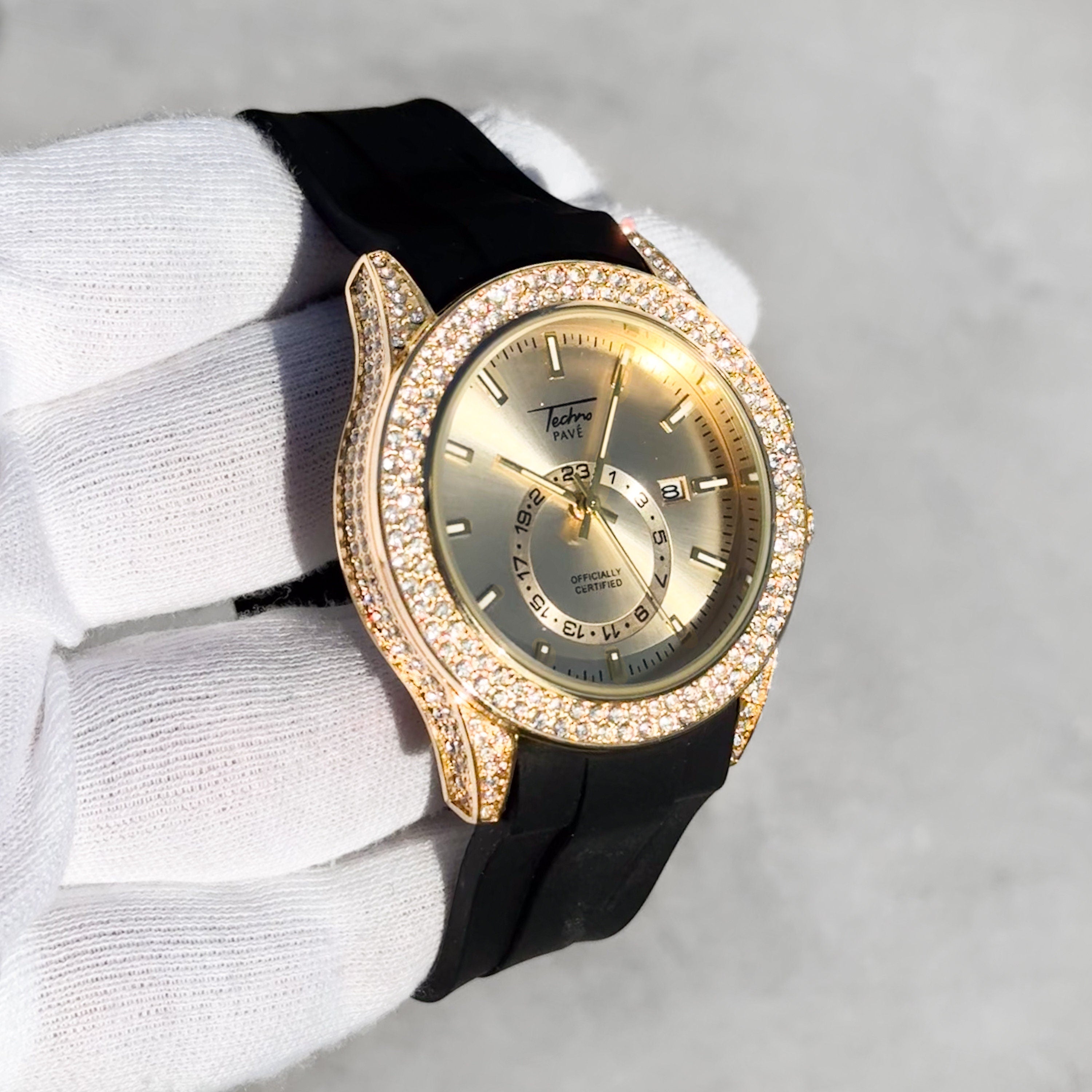 Gold 42mm men’s quartz watch featuring an iced bezel, champagne dial, and black silicone strap.