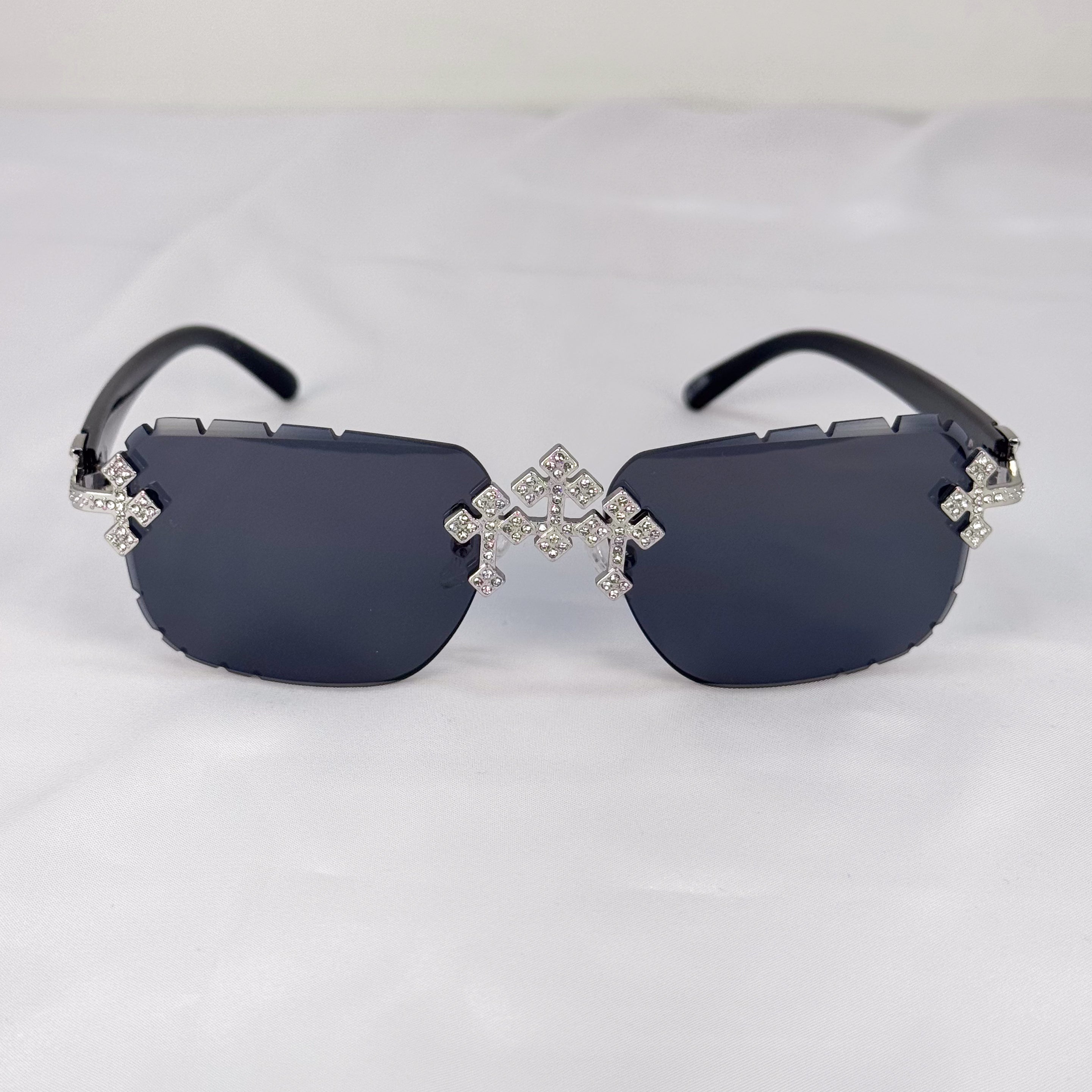 Rimless black lens sunglasses with sparkling iced triple cross hardware and black curved arms.
