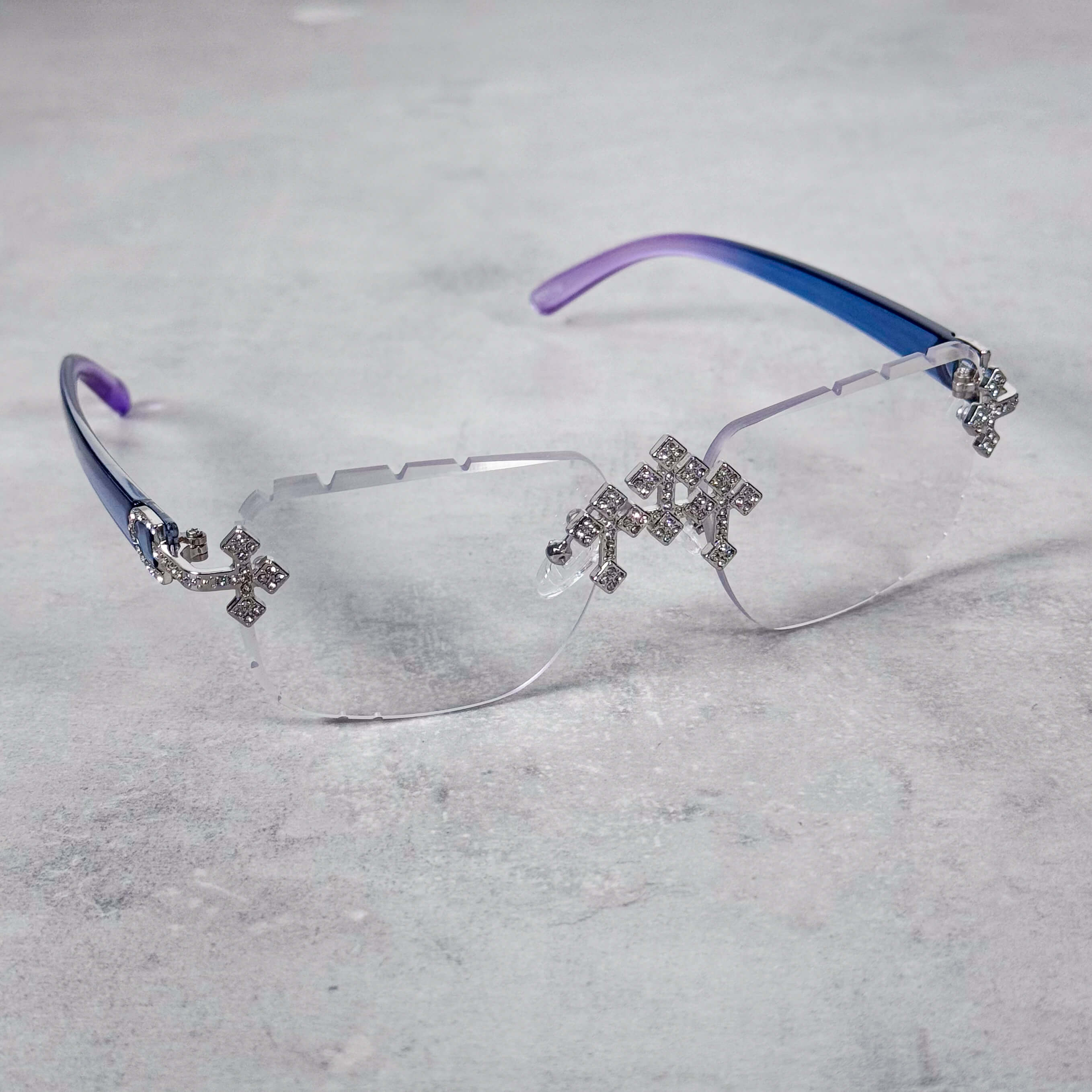 Rimless clear Iced Triple Cross Sunglasses with sparkling cross details and blue-purple temples.