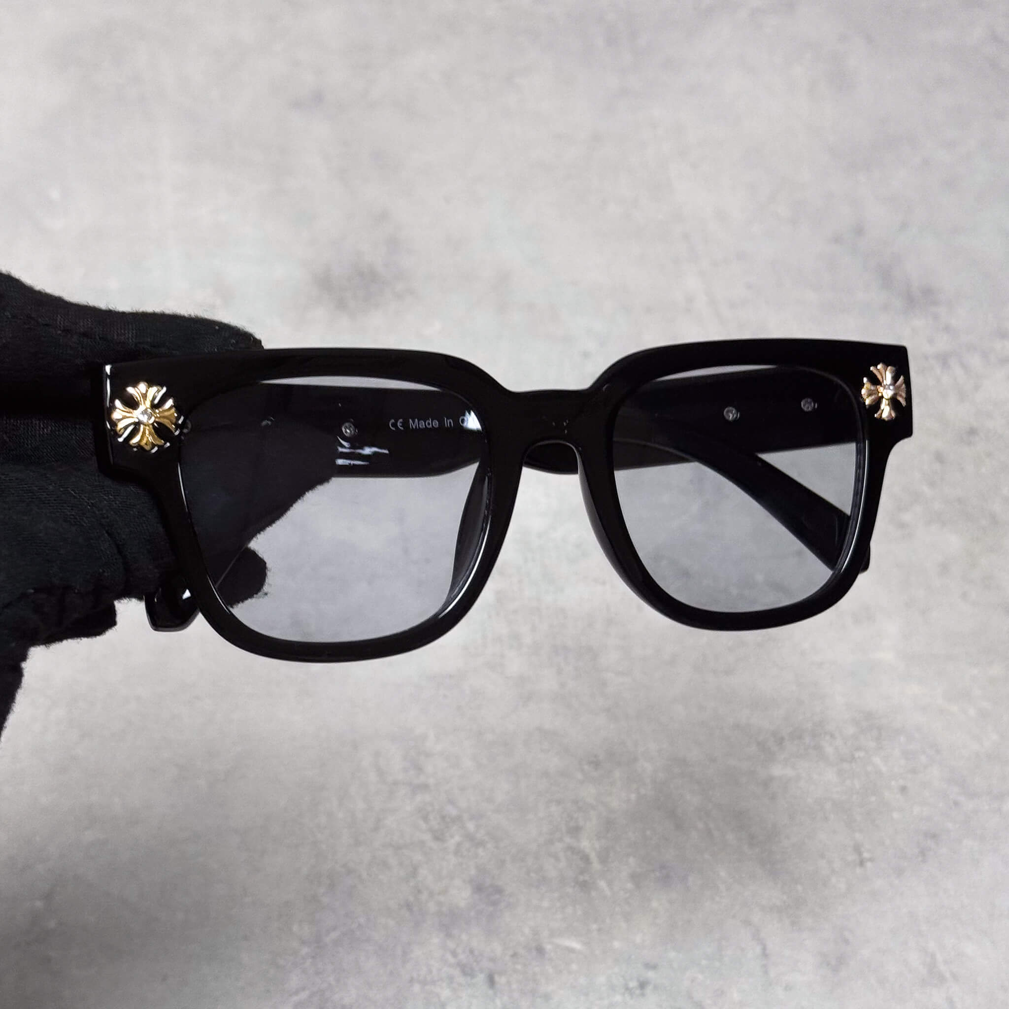 Front view of black Cross Chrome Inspired Sunglasses featuring smoke lenses and gold cross studs.