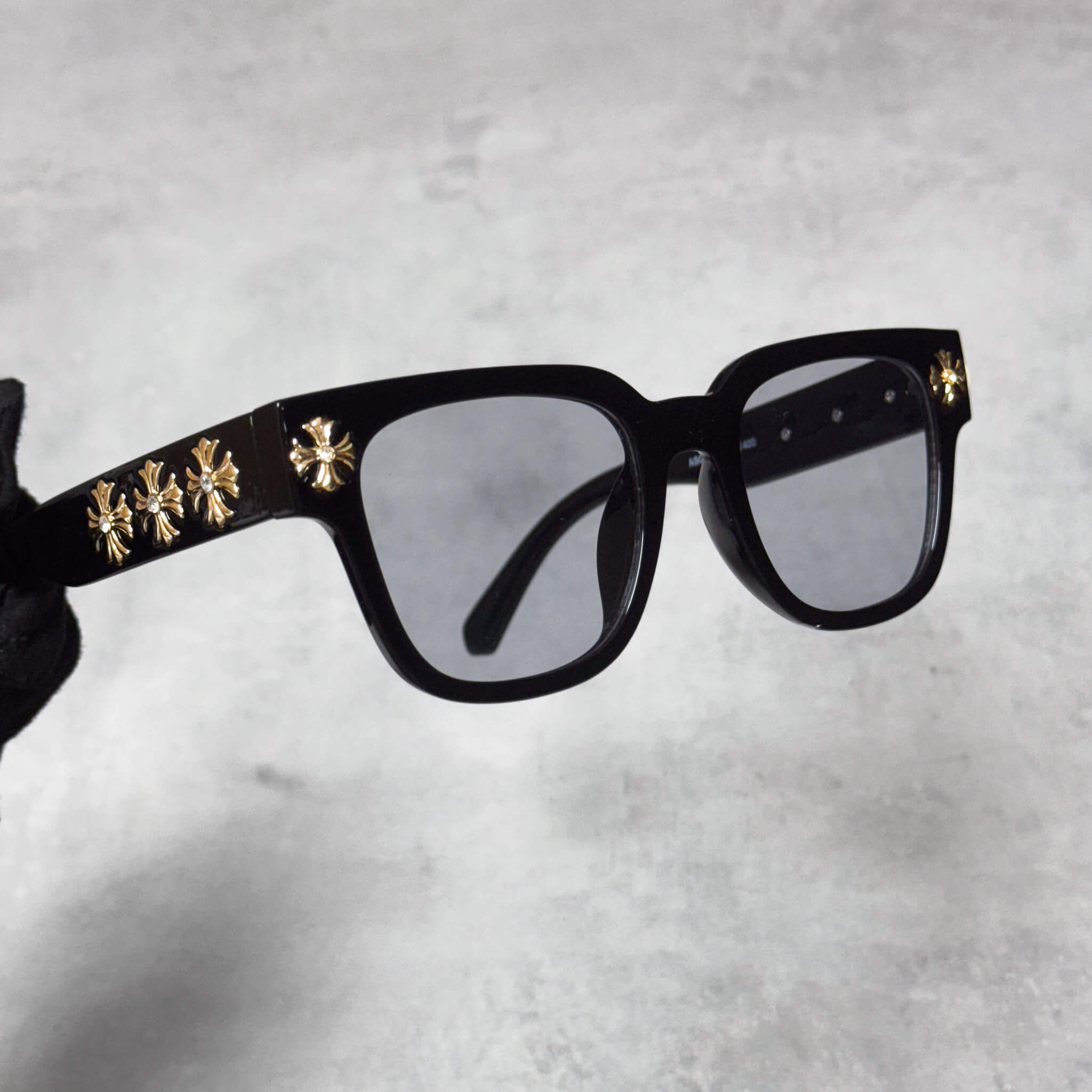 Side angle of Cross Chrome Inspired Sunglasses with smoke lenses and gold chrome cross detailing.