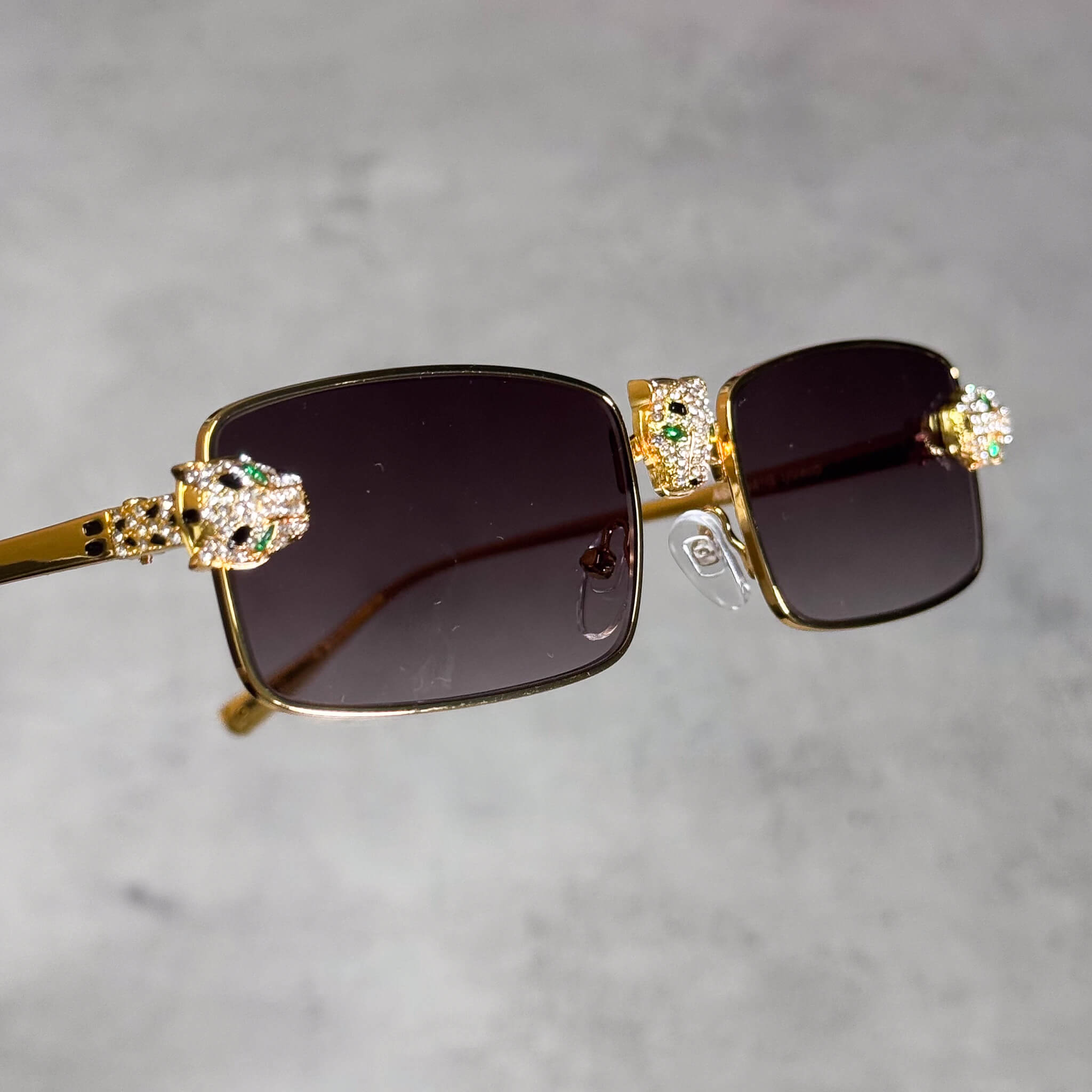 Gold smoke-lens rectangular sunglasses featuring iced-out panther heads and luxury trim.