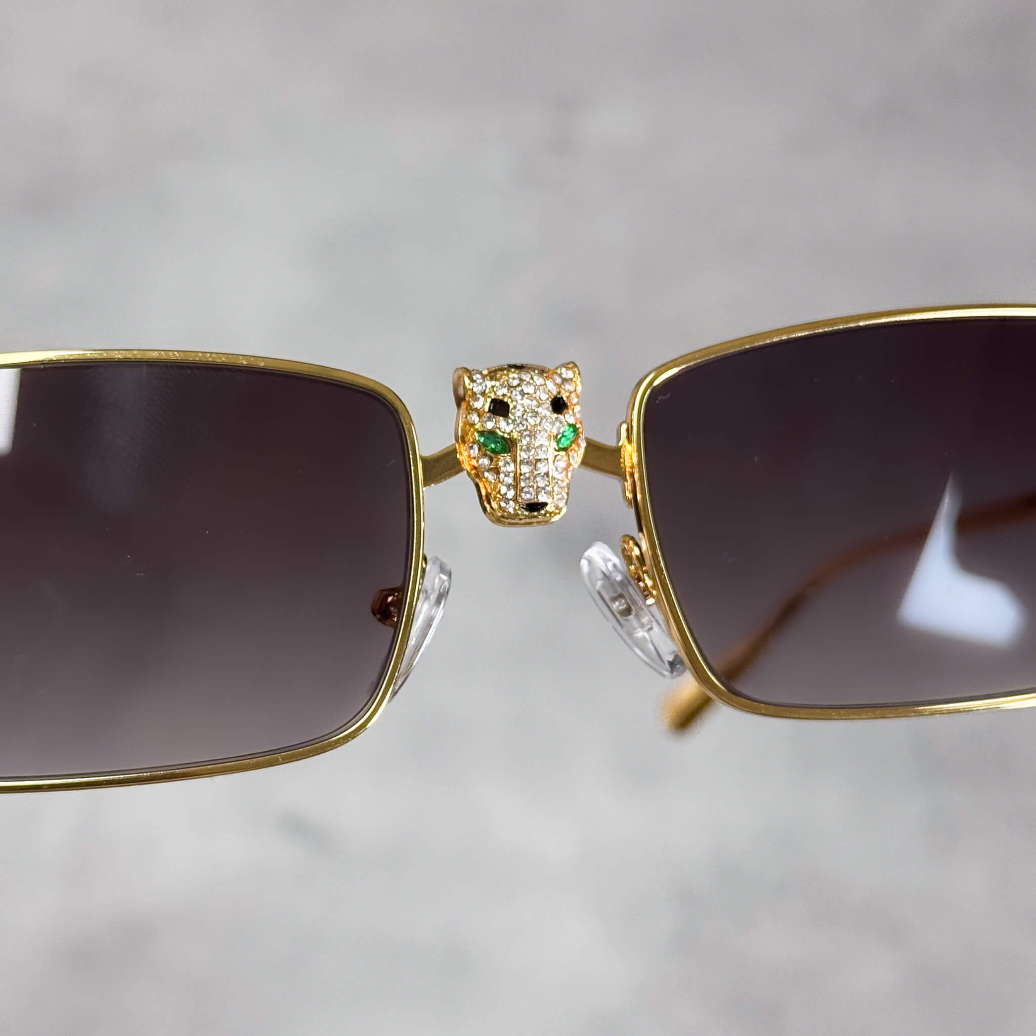 Front view of gold Iced Out Panther Sunglasses with smoke lenses and crystal panther centerpiece.