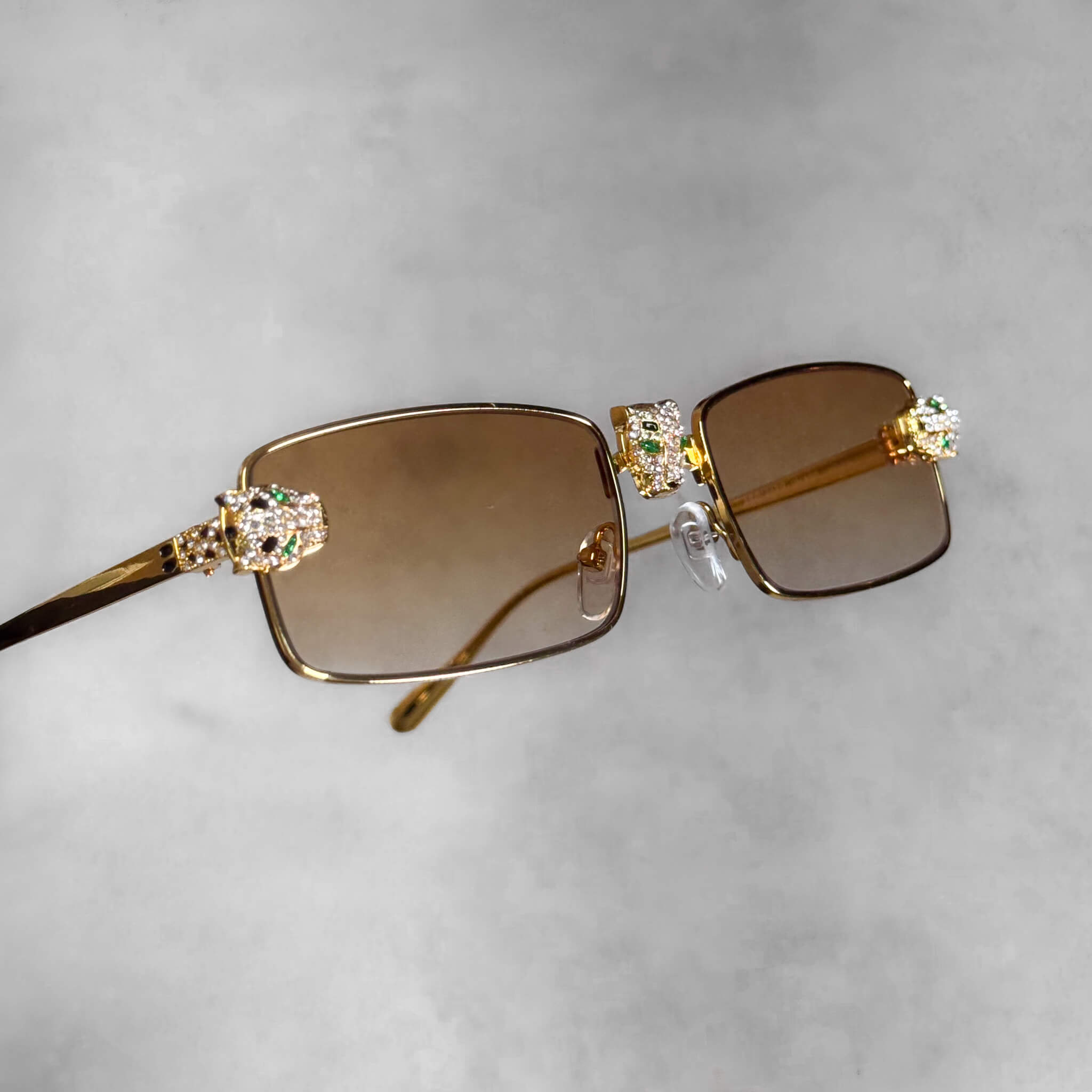 Yellow-lens rectangular sunglasses featuring gold frames and iced-out panther head details.
