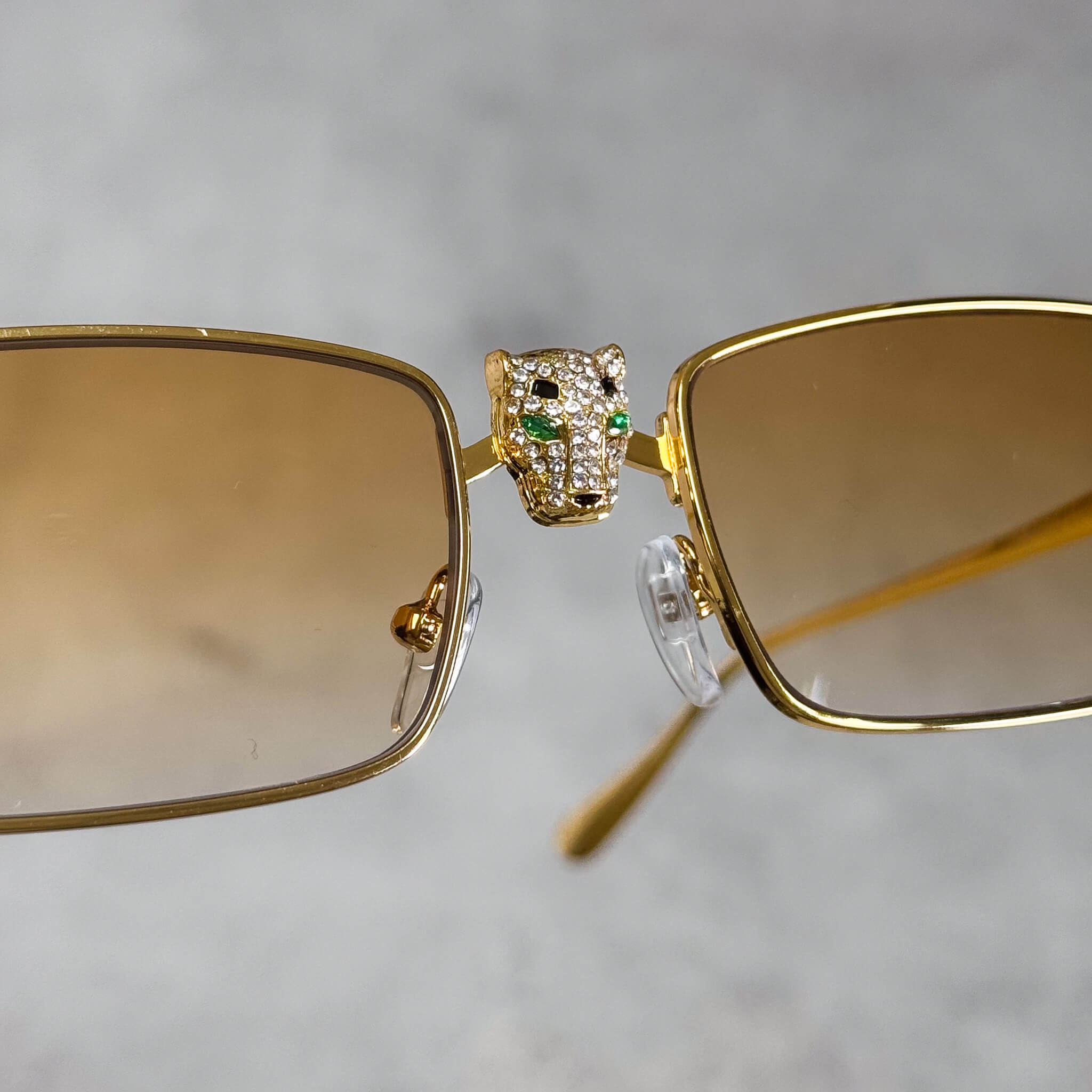 Close-up of gold panther centerpiece on yellow-lens Iced Out Panther Sunglasses with crystals.