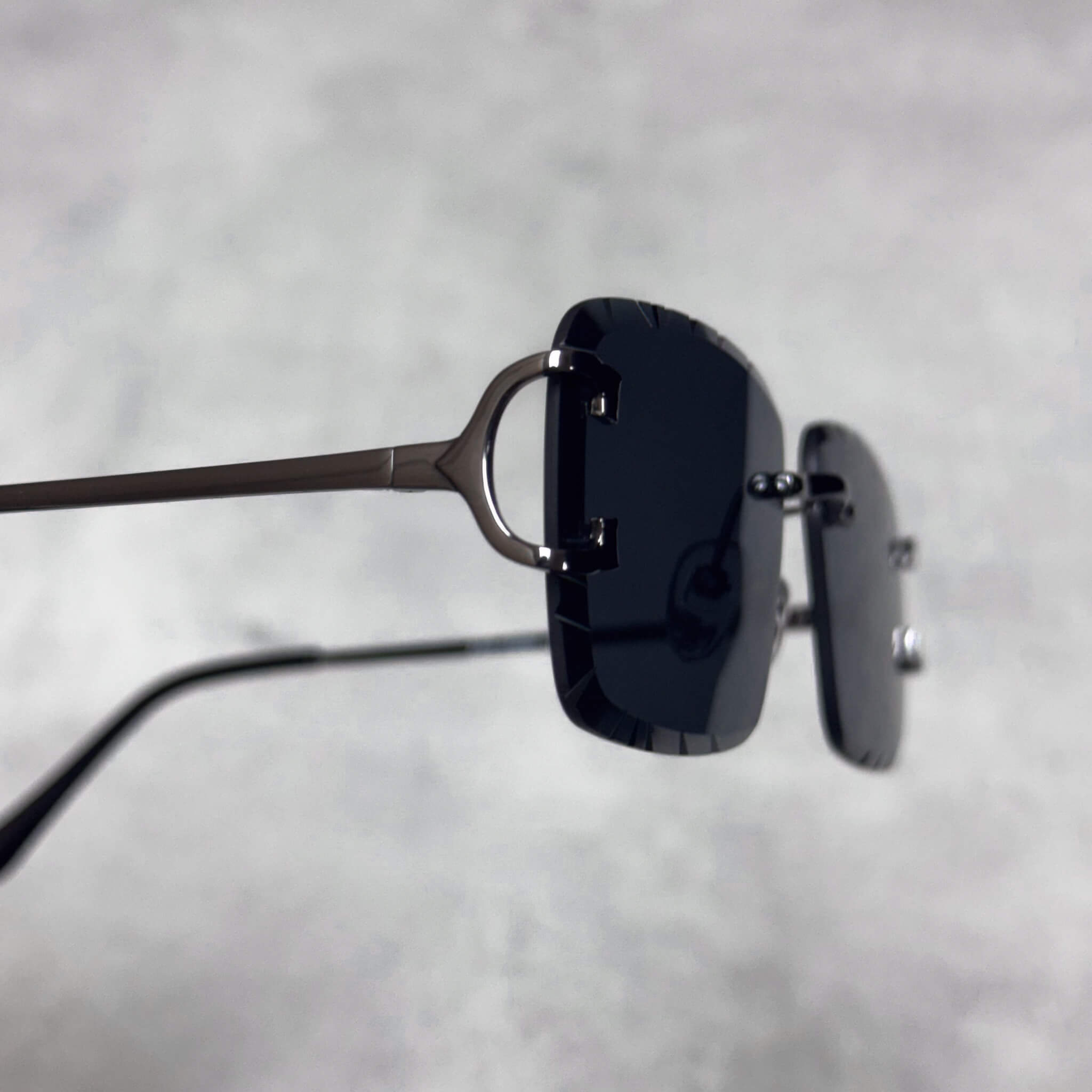 Close-up of Solid Cut-Edge Sunglasses showing black square lens and sleek black temple.