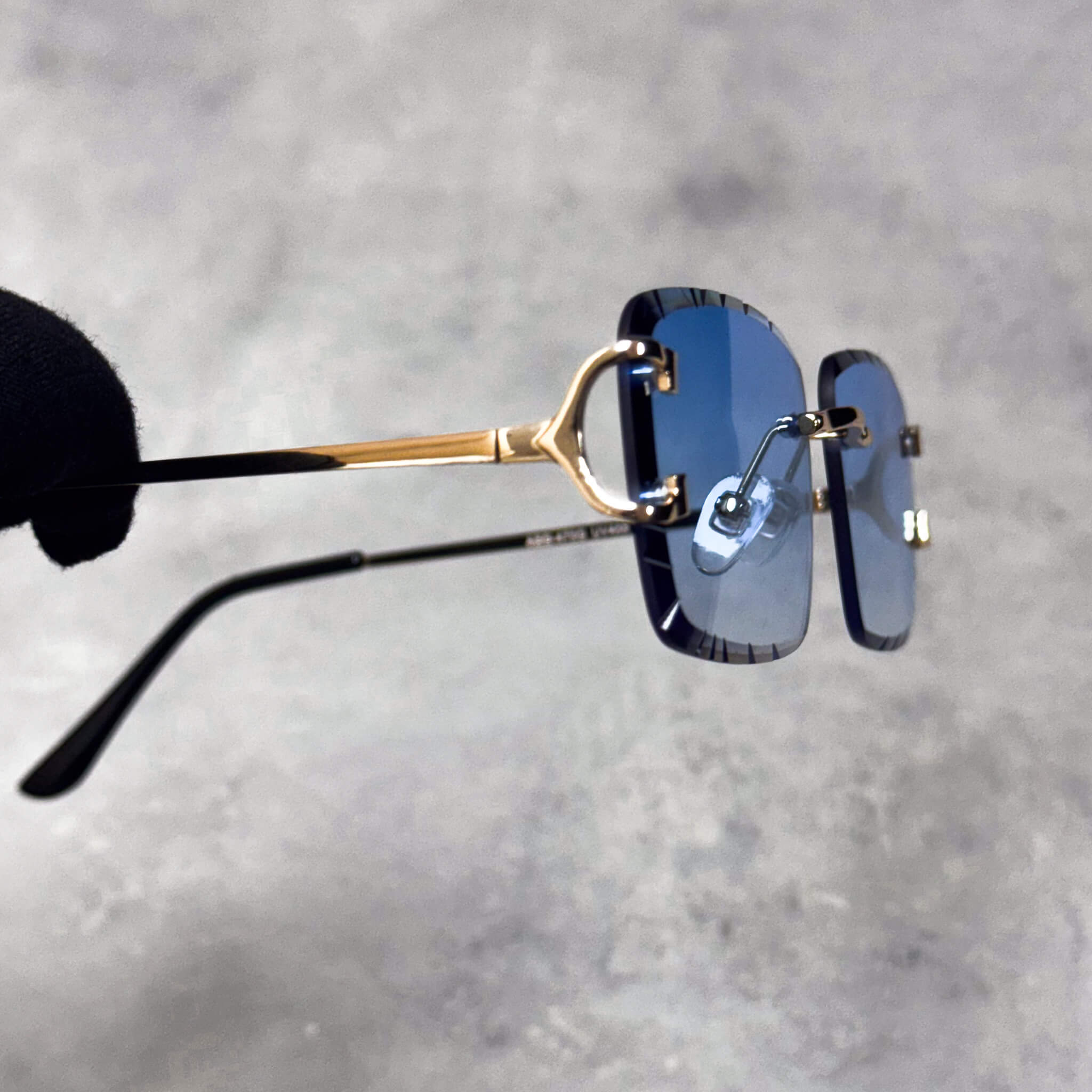 Side view of blue Solid Cut-Edge Sunglasses with gold metal temples and rimless square lenses.