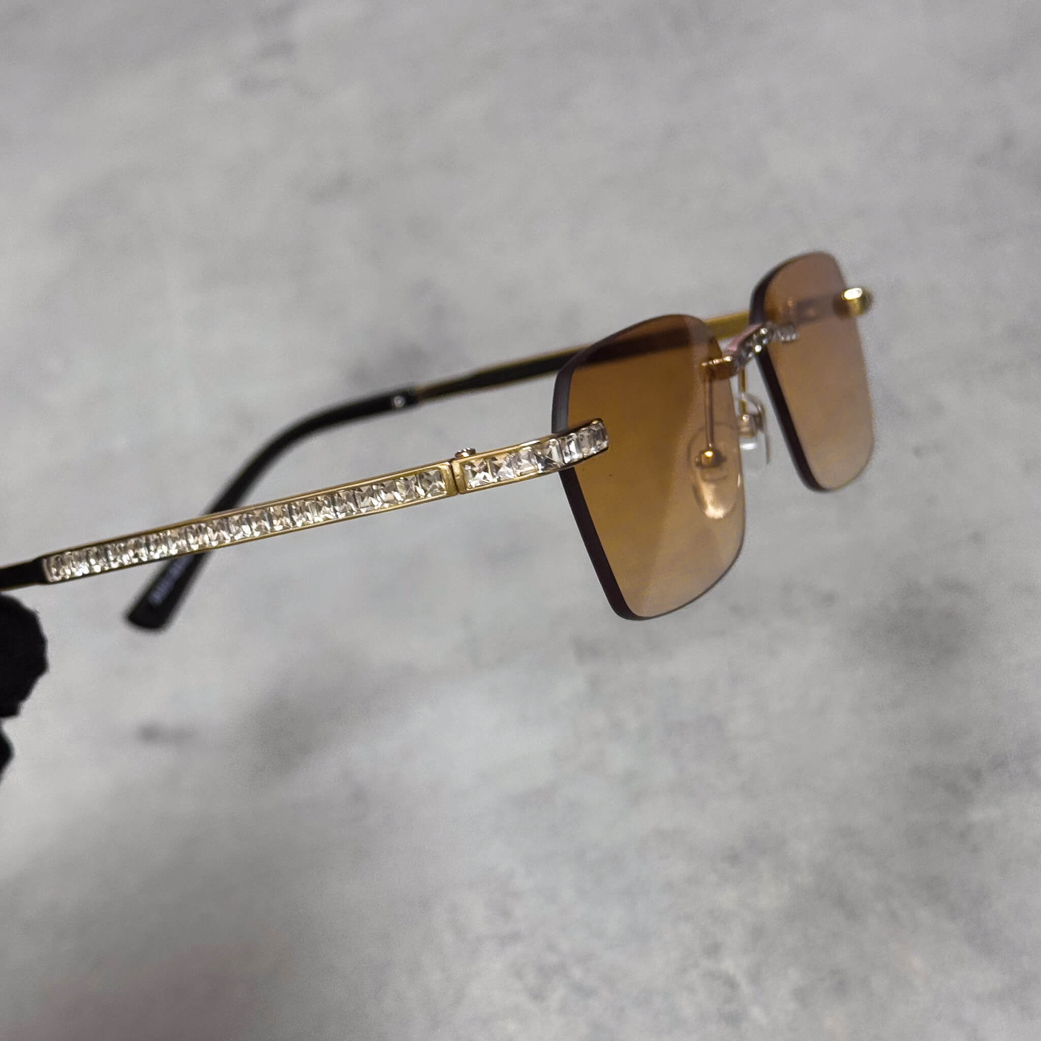 Brown lens baguette stone sunglasses featuring gold temples with crystal side detailing.