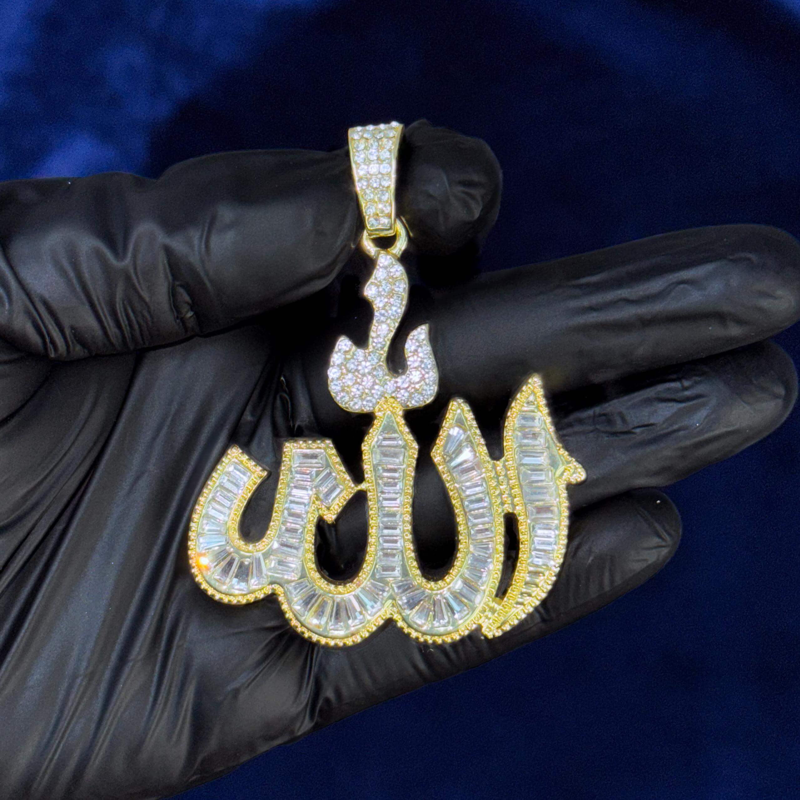 Gold iced-out baguette Allah pendant displayed in gloved hand showcasing stone detailing.