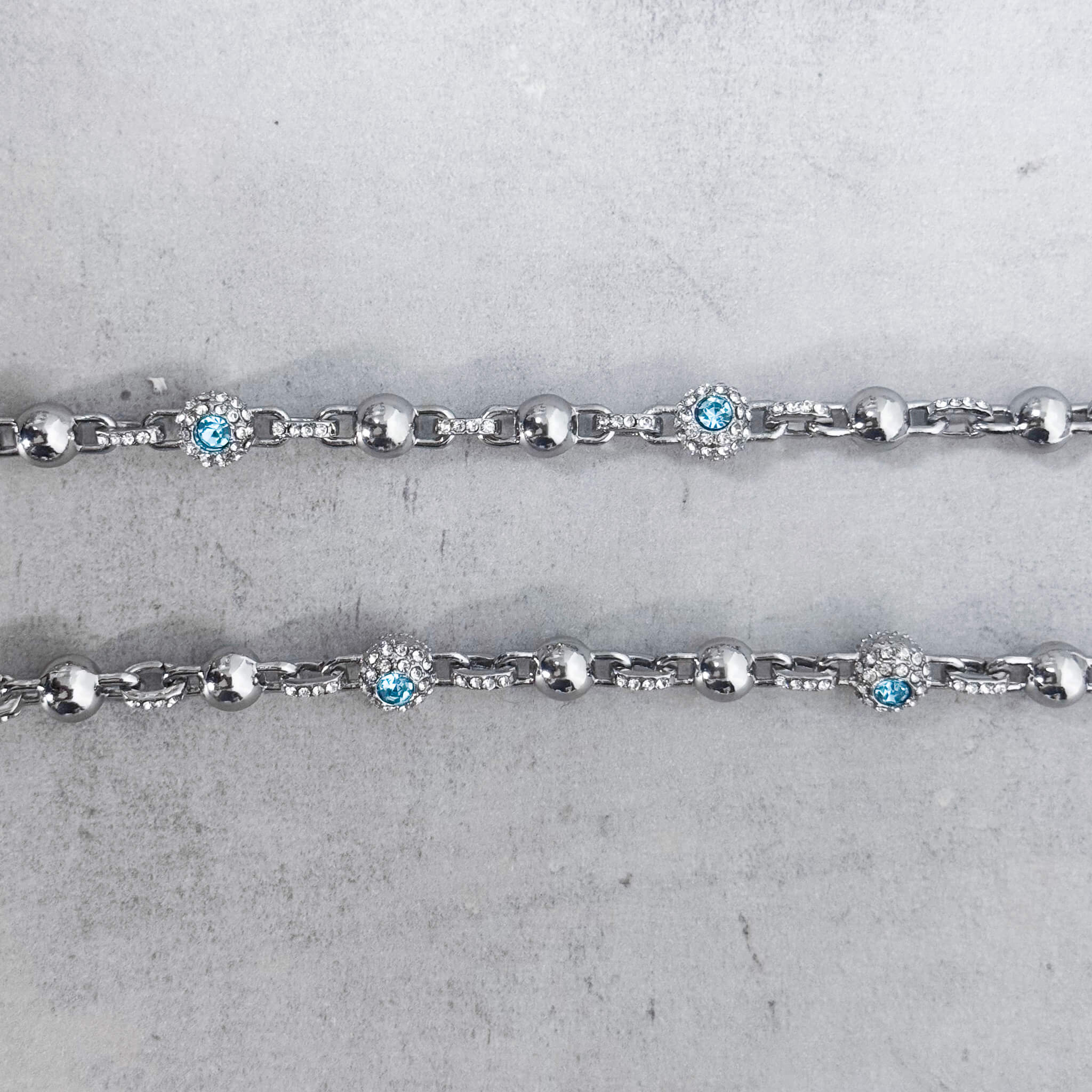 Close-up of silver Iced Out Ball Pant Chain showcasing blue crystal centers and sparkling diamond accents.