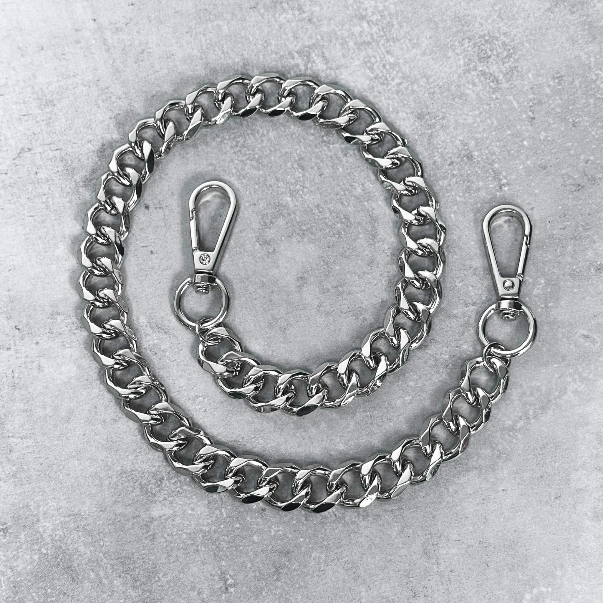 Solid 10mm Cuban link pant chain in polished silver metal, shown coiled with secure clasp hardware.