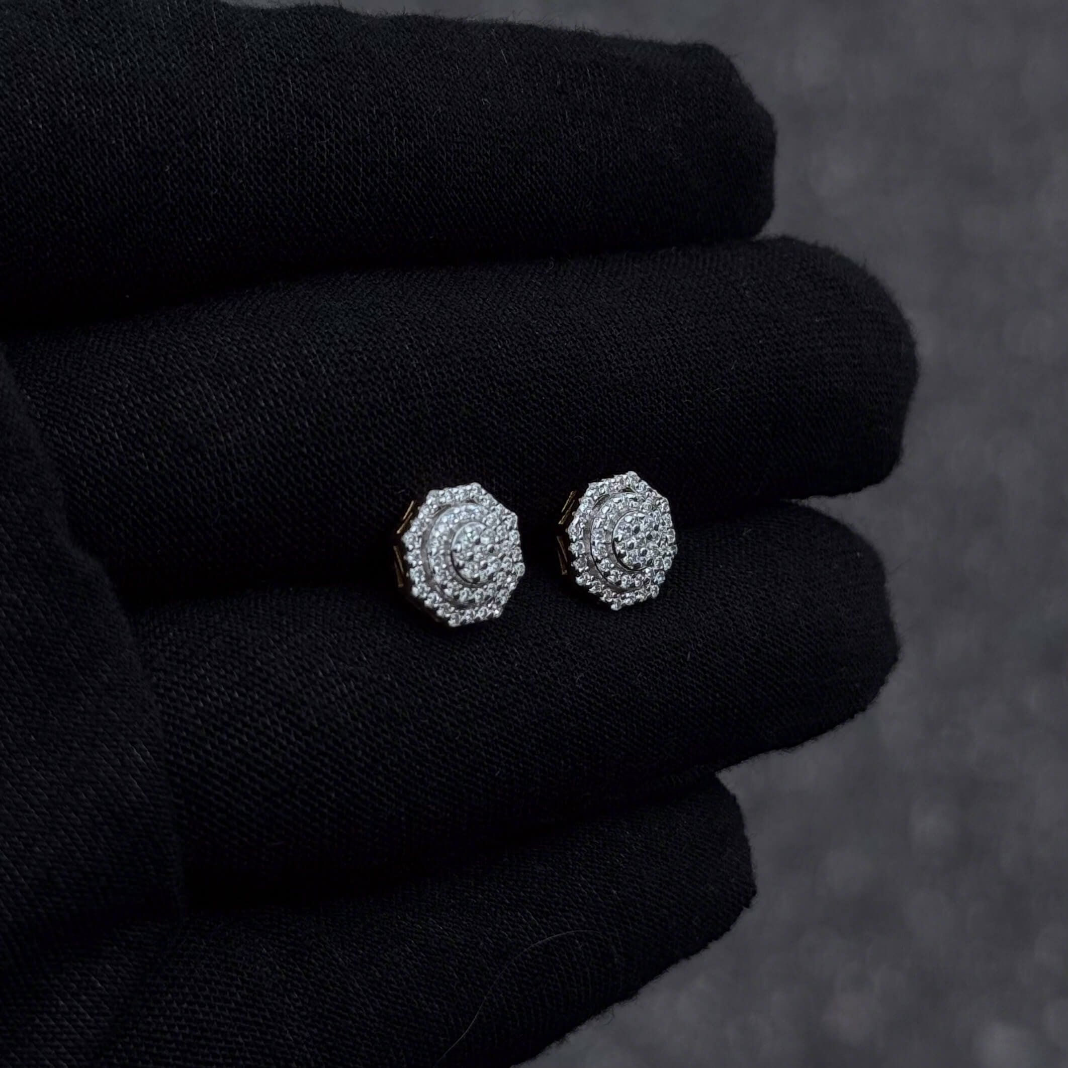 Moissanite octagon cluster diamond studs in sterling silver displayed on black glove.