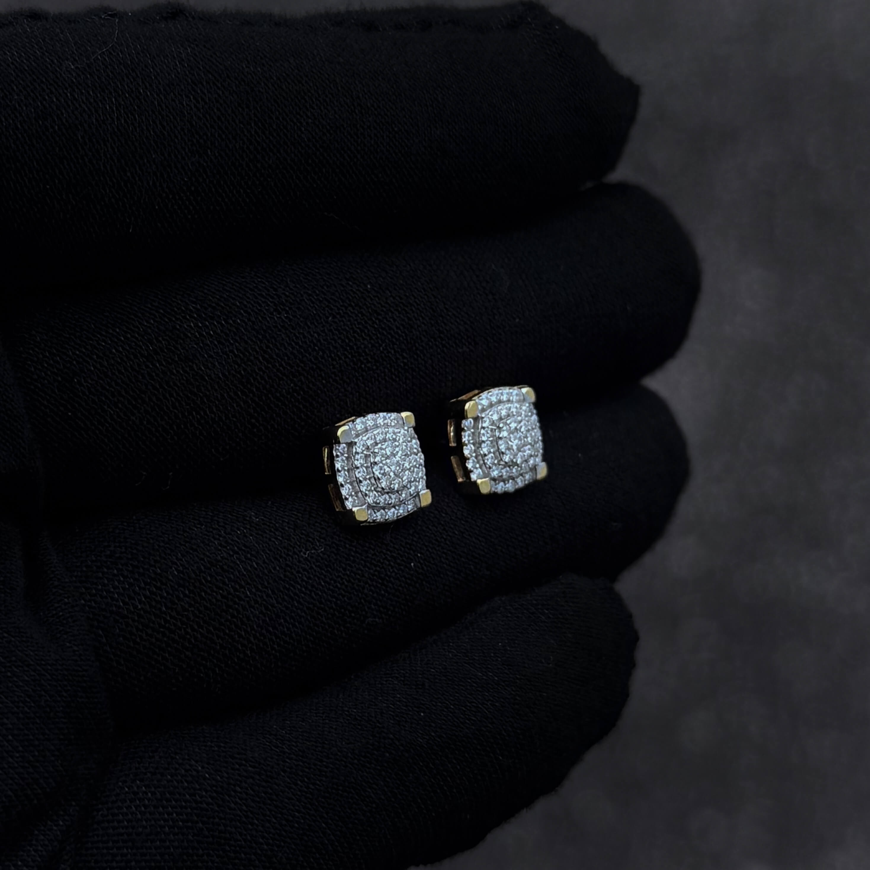 Angled view of 9mm moissanite cluster earrings with 0.5ct diamonds and gold accents on black glove.