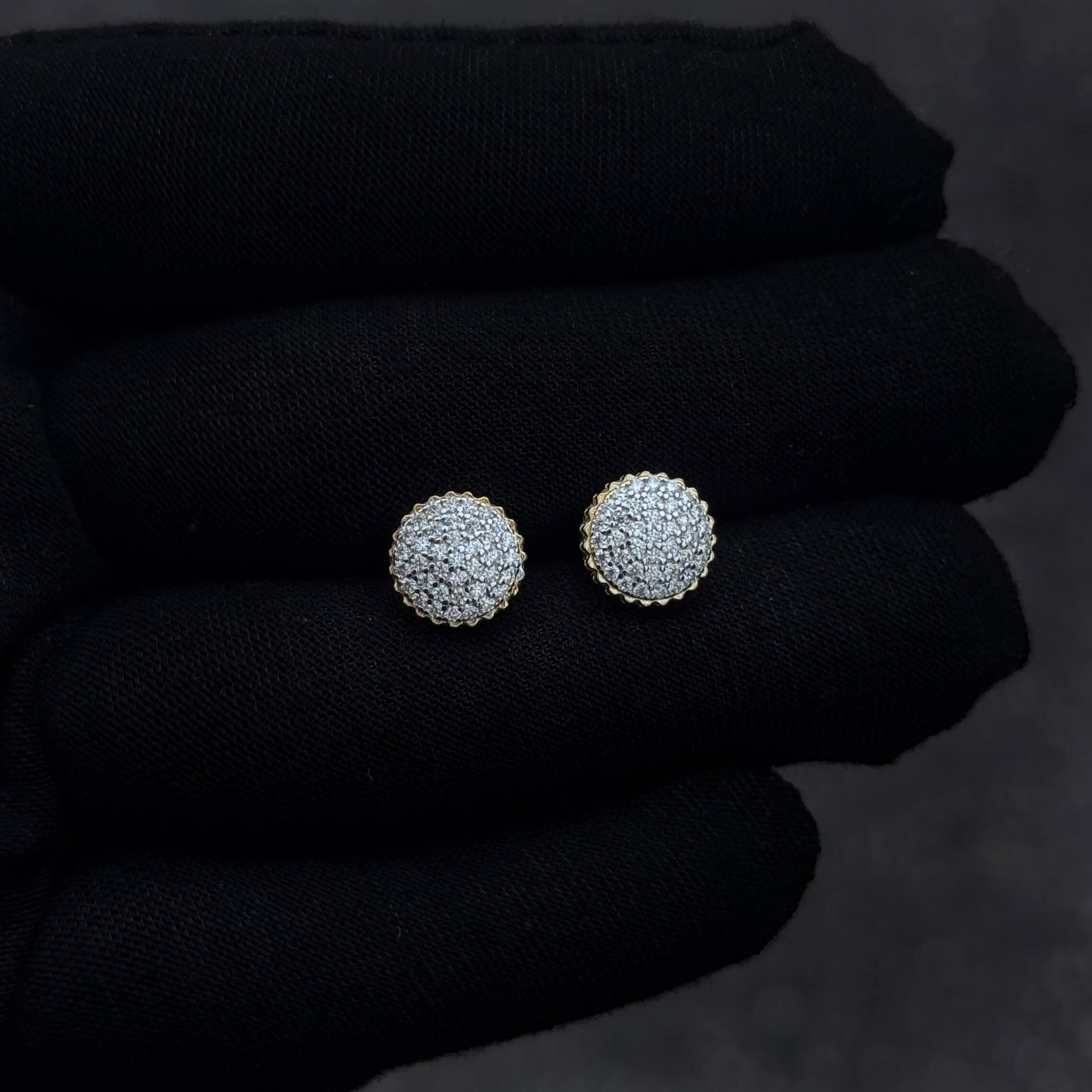 Small round 9mm moissanite diamond cluster studs shown on black glove, gold scalloped border and pavé setting.