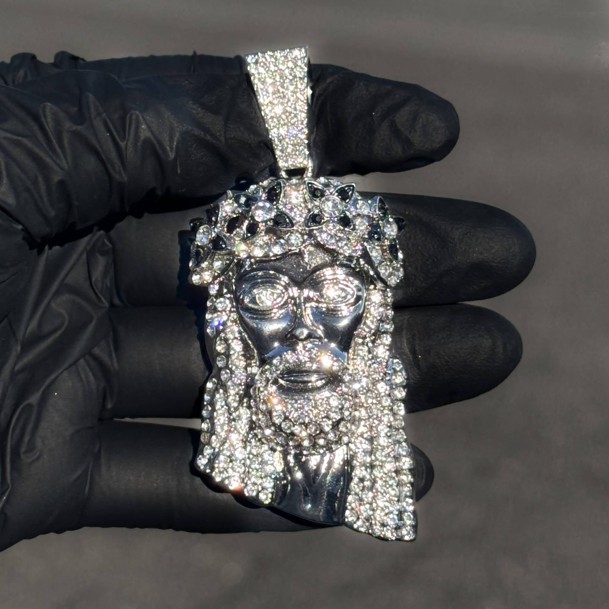 Silver iced-out Jesus pendant with black spiked crown accents and shimmering pavé detailing.