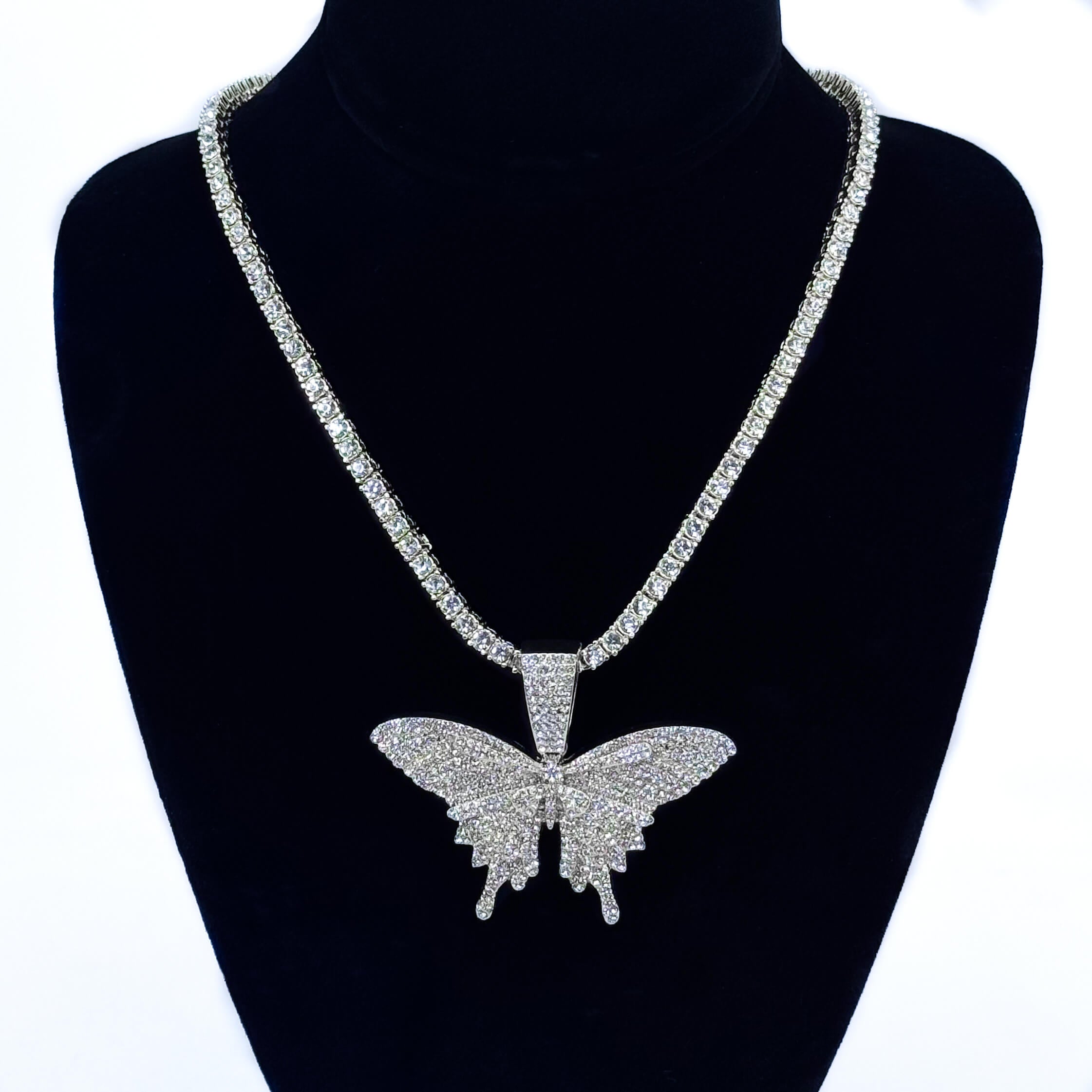 Ladies 60mm iced-out silver butterfly pendant necklace with 4mm tennis chain on jewelry bust.